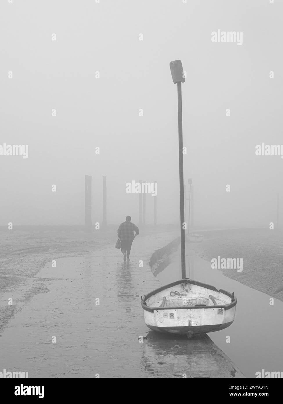Barche nella nebbia con pali, mulino a spille d'arte Suffolk con una persona che se ne va Foto Stock