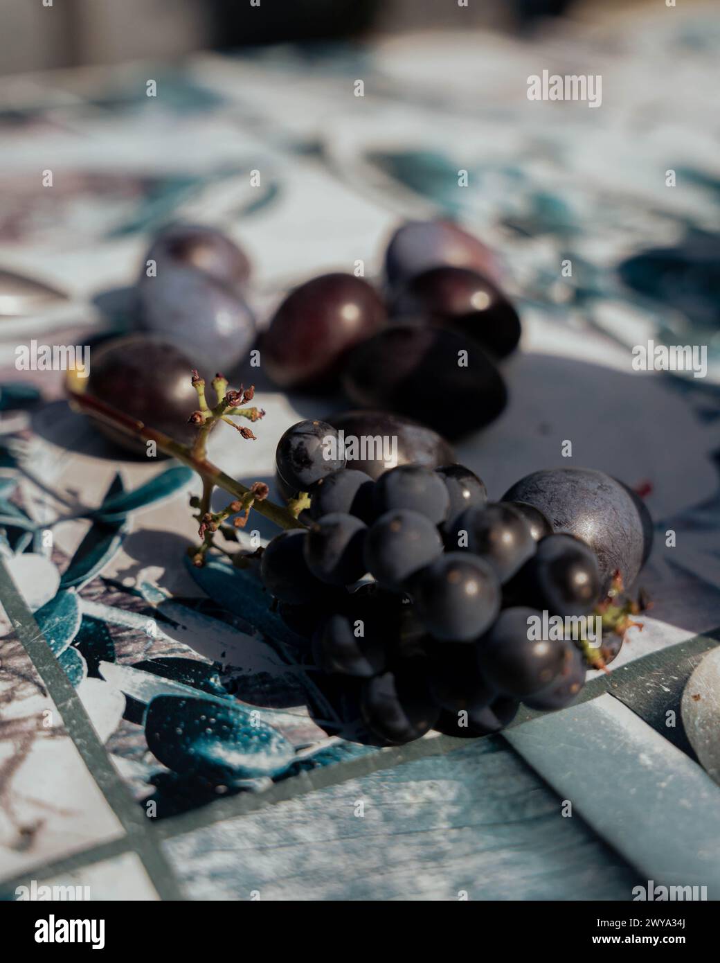 Uva sul tavolo. Luce naturale. Bei ricordi. Sfondo blu maculato. Foto Stock