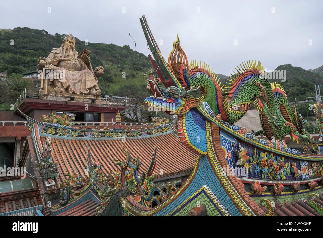 Vista grandangolare con tetto del tempio Chuen Ji Hall decorato con draghi e statua colossale sullo sfondo Foto Stock