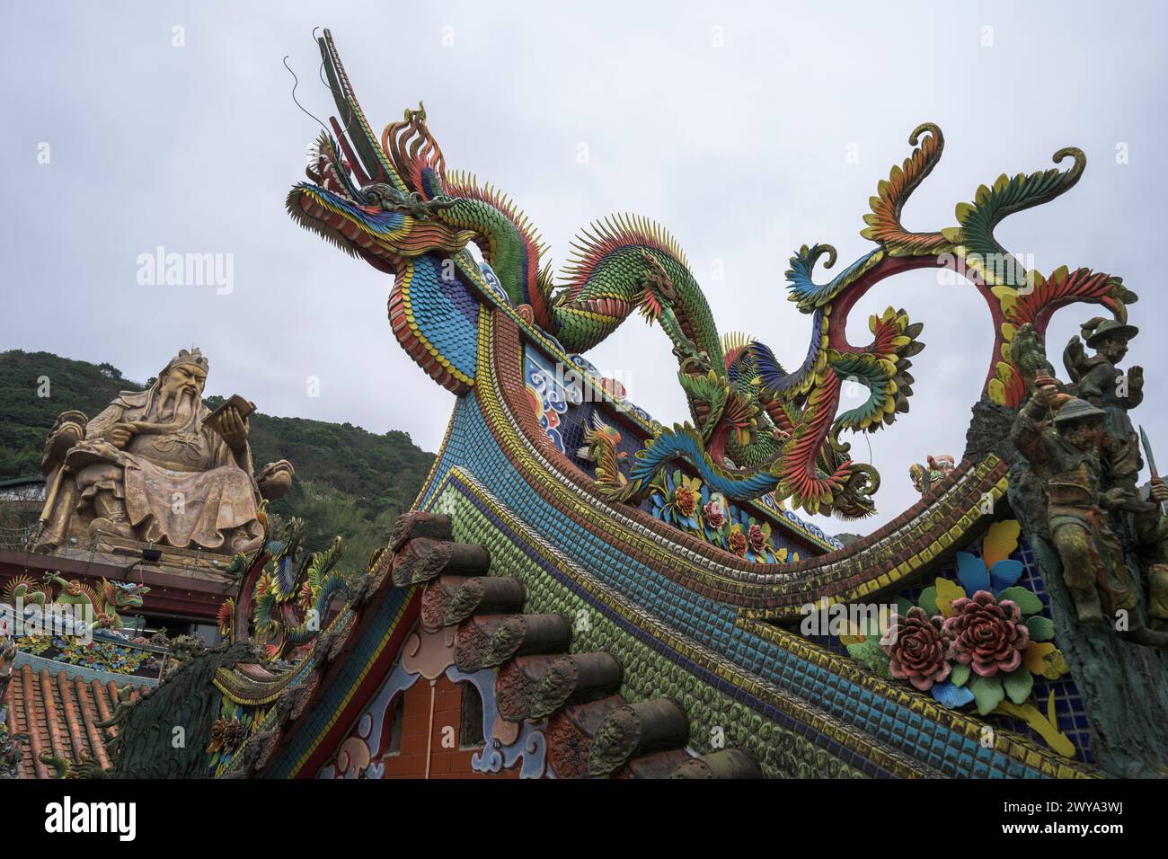 Ammira il tetto del tempio Chuen Ji Hall decorato con draghi e una colossale statua sullo sfondo Foto Stock