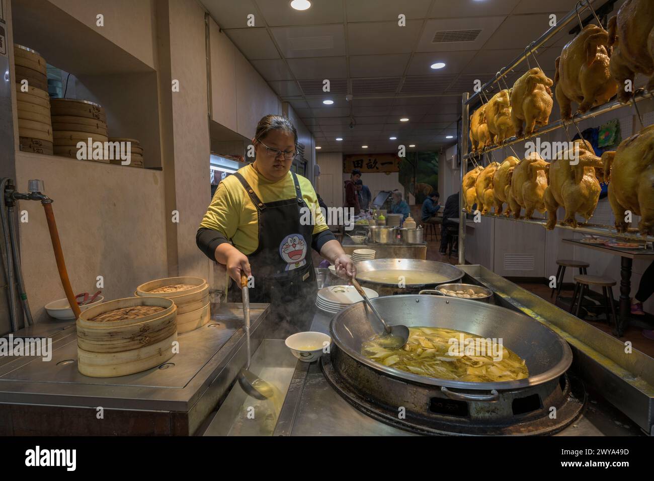 Una donna che serve piatti tradizionali cinesi in una bancarella di cibo nelle strade di Jiufen Foto Stock