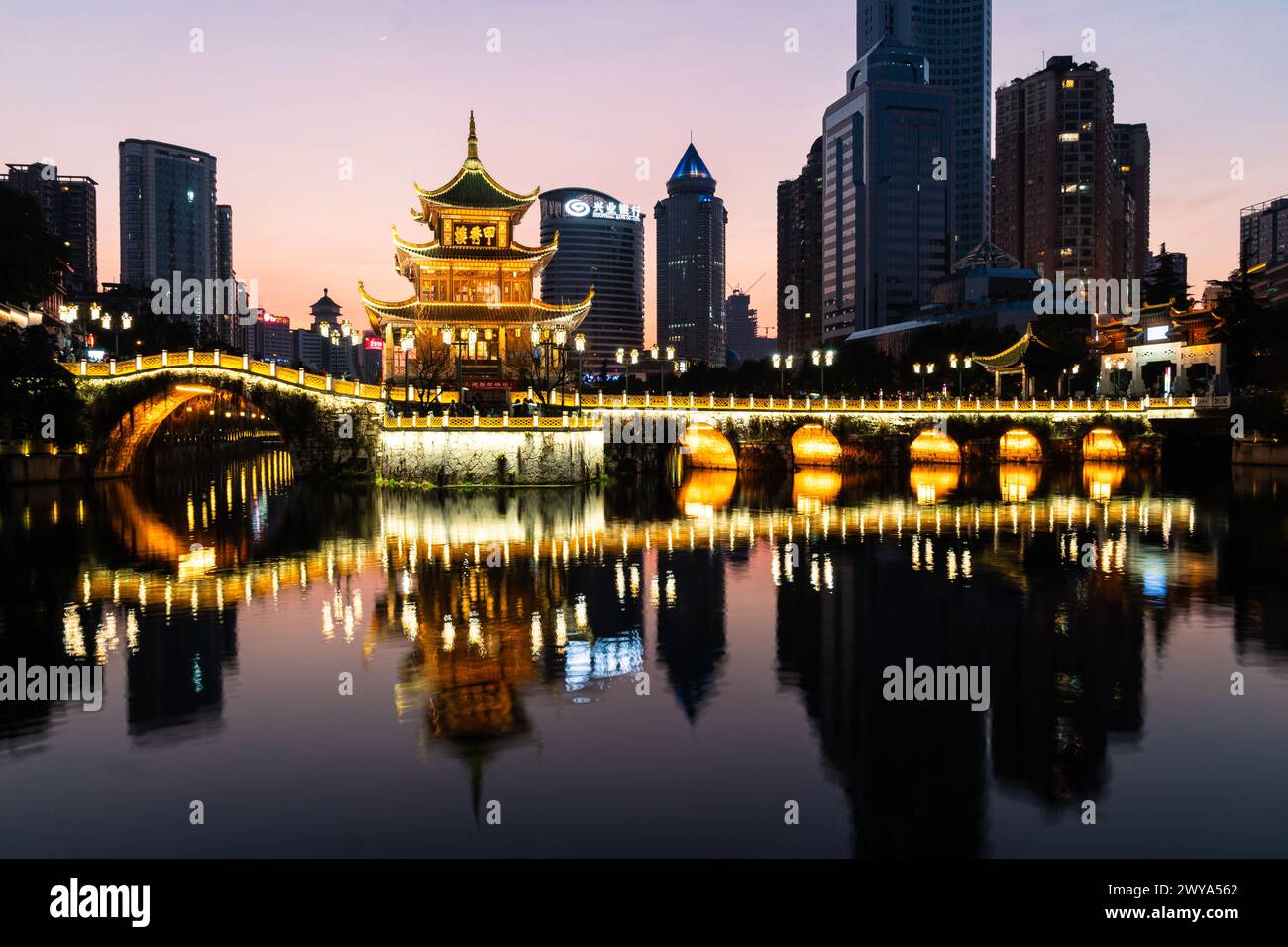 Guiyang, Cina - 09 febbraio 2022: La famosa torre Jiaxiu e il ponte Fuyu si riflettono sul fiume nel cuore del centro di Guiyang nel sud-ovest della città Foto Stock