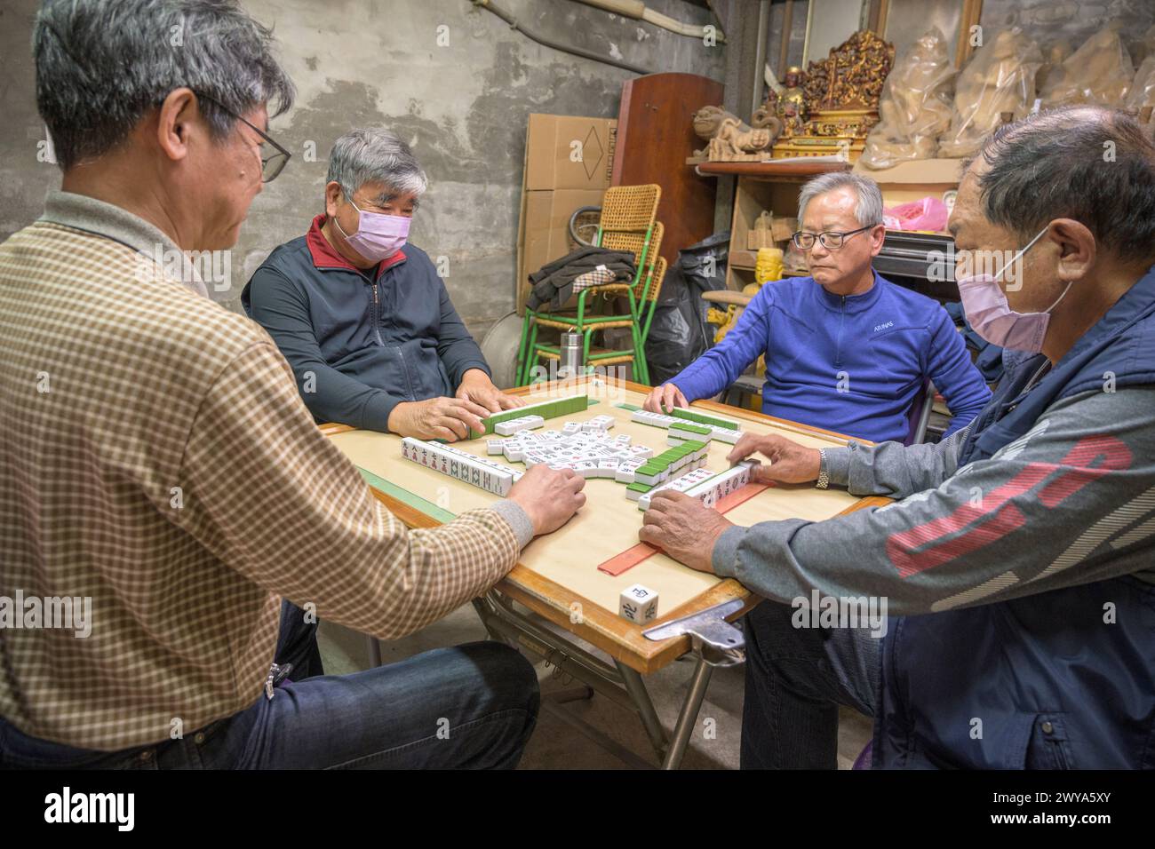 Gruppo di uomini impegnati in una partita di mahjong in un ambiente informale Foto Stock