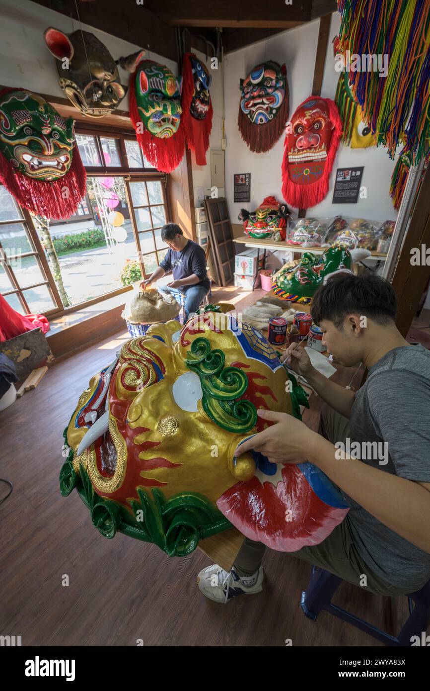 Gli artigiani lavorano su vibranti maschere cerimoniali in un tradizionale studio di artigianato a Lukang Foto Stock