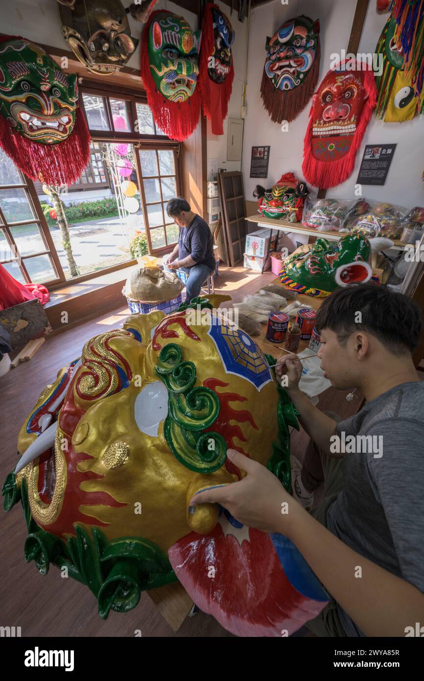 Gli artigiani lavorano su vibranti maschere cerimoniali in un tradizionale studio di artigianato a Lukang Foto Stock