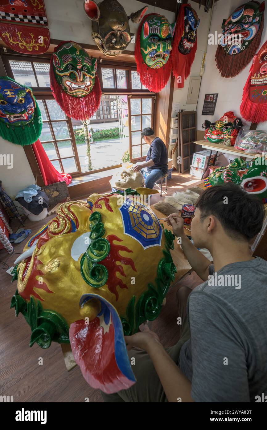 Gli artigiani lavorano su vibranti maschere cerimoniali in un tradizionale studio di artigianato a Lukang Foto Stock