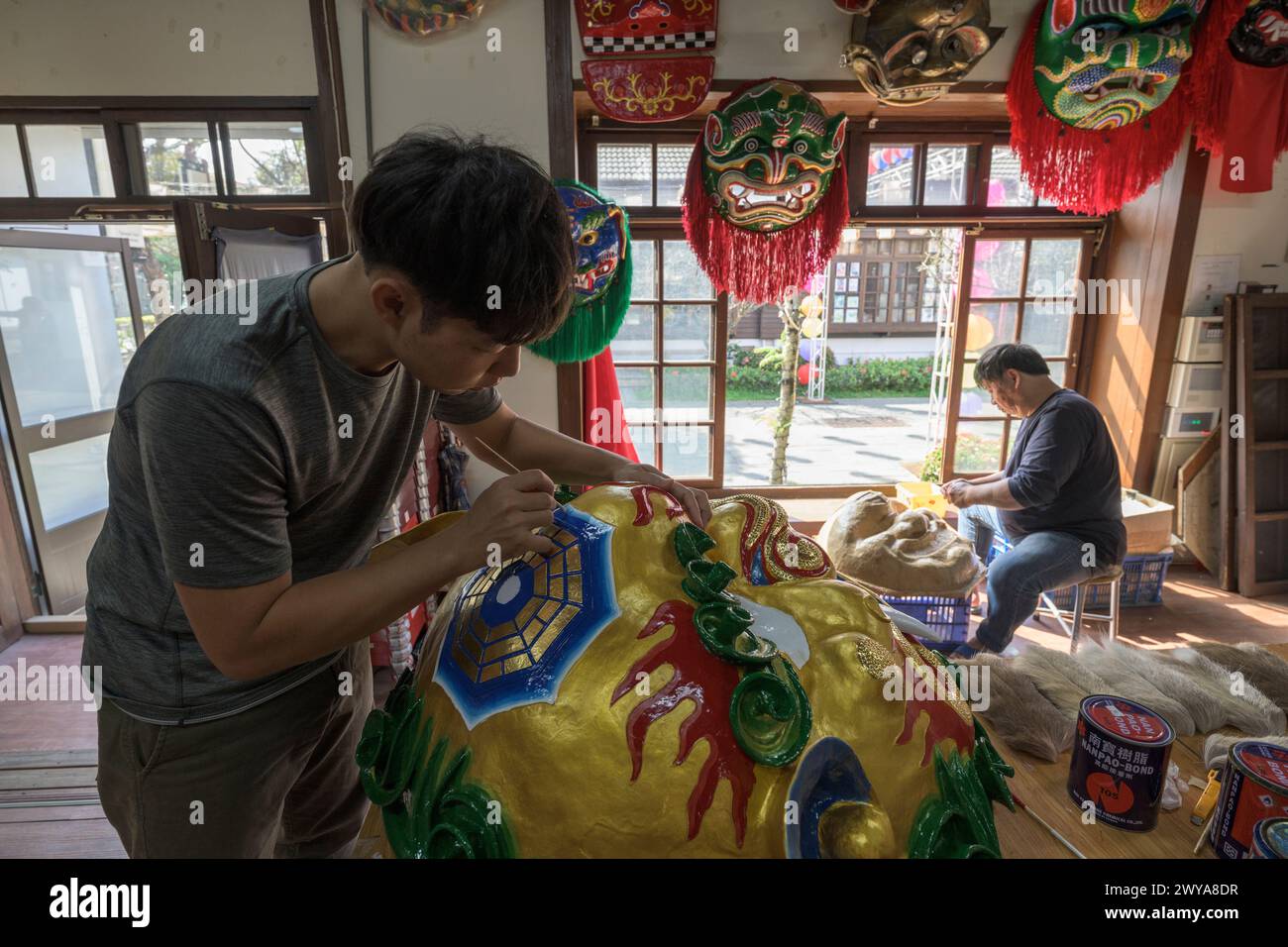 Gli artigiani lavorano su vibranti maschere cerimoniali in un tradizionale studio di artigianato a Lukang Foto Stock