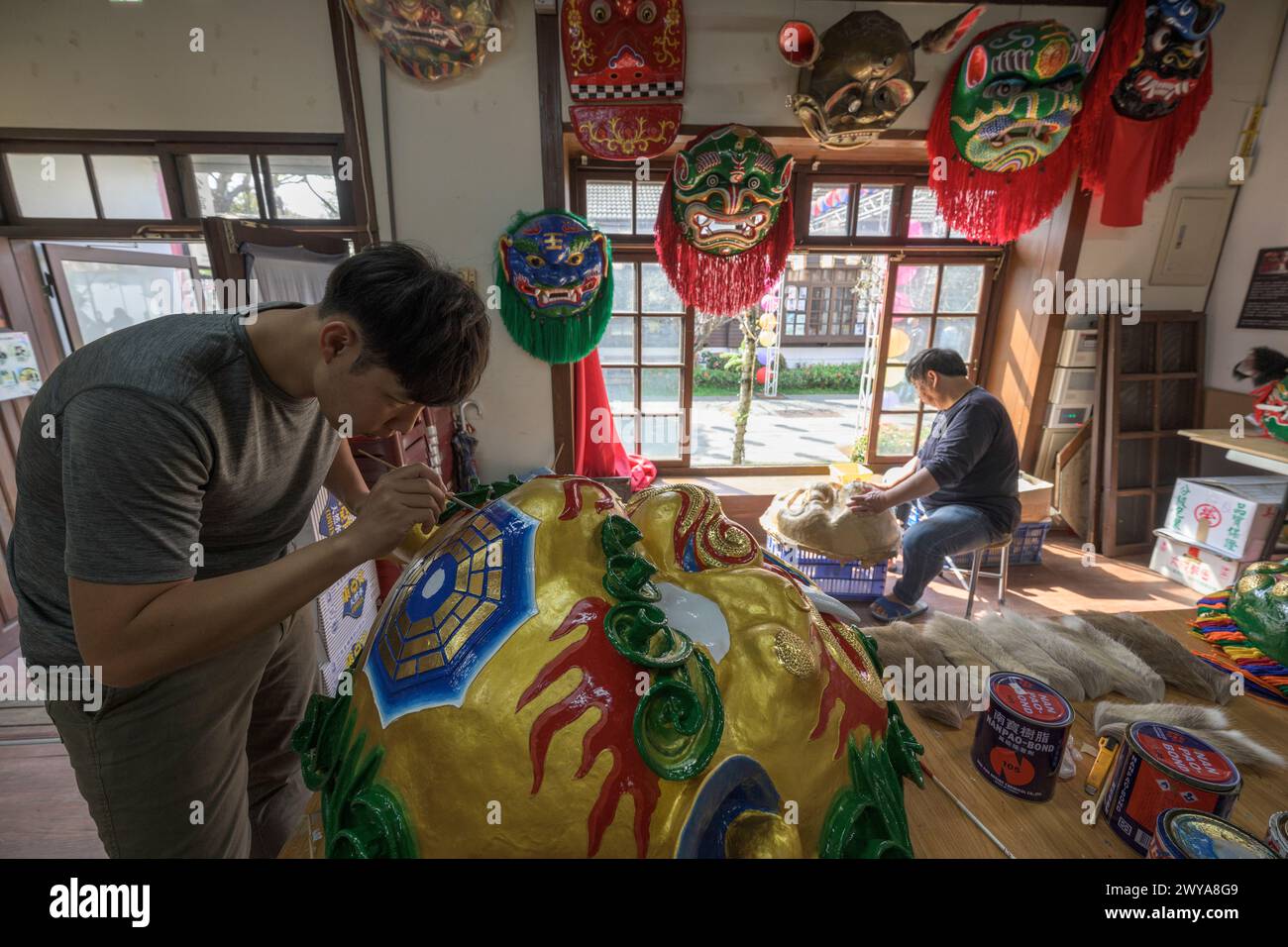 Gli artigiani lavorano su vibranti maschere cerimoniali in un tradizionale studio di artigianato a Lukang Foto Stock