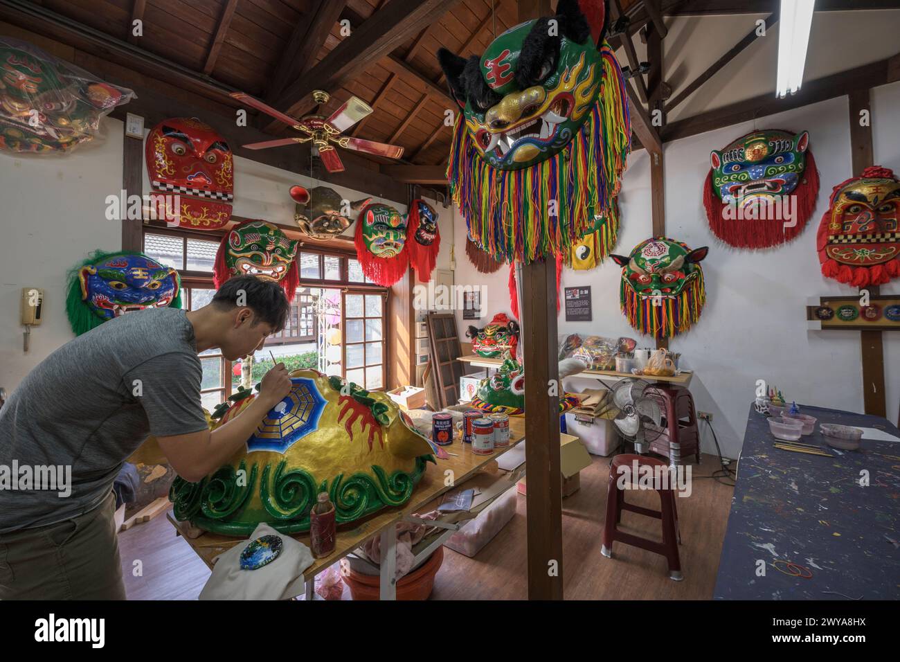 Gli artigiani lavorano su vibranti maschere cerimoniali in un tradizionale studio di artigianato a Lukang Foto Stock