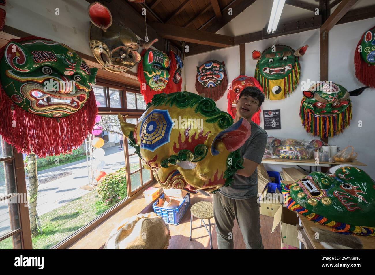 Artigiano che mostra le maschere cerimoniali che produce in un tradizionale studio di artigianato a Lukang Foto Stock