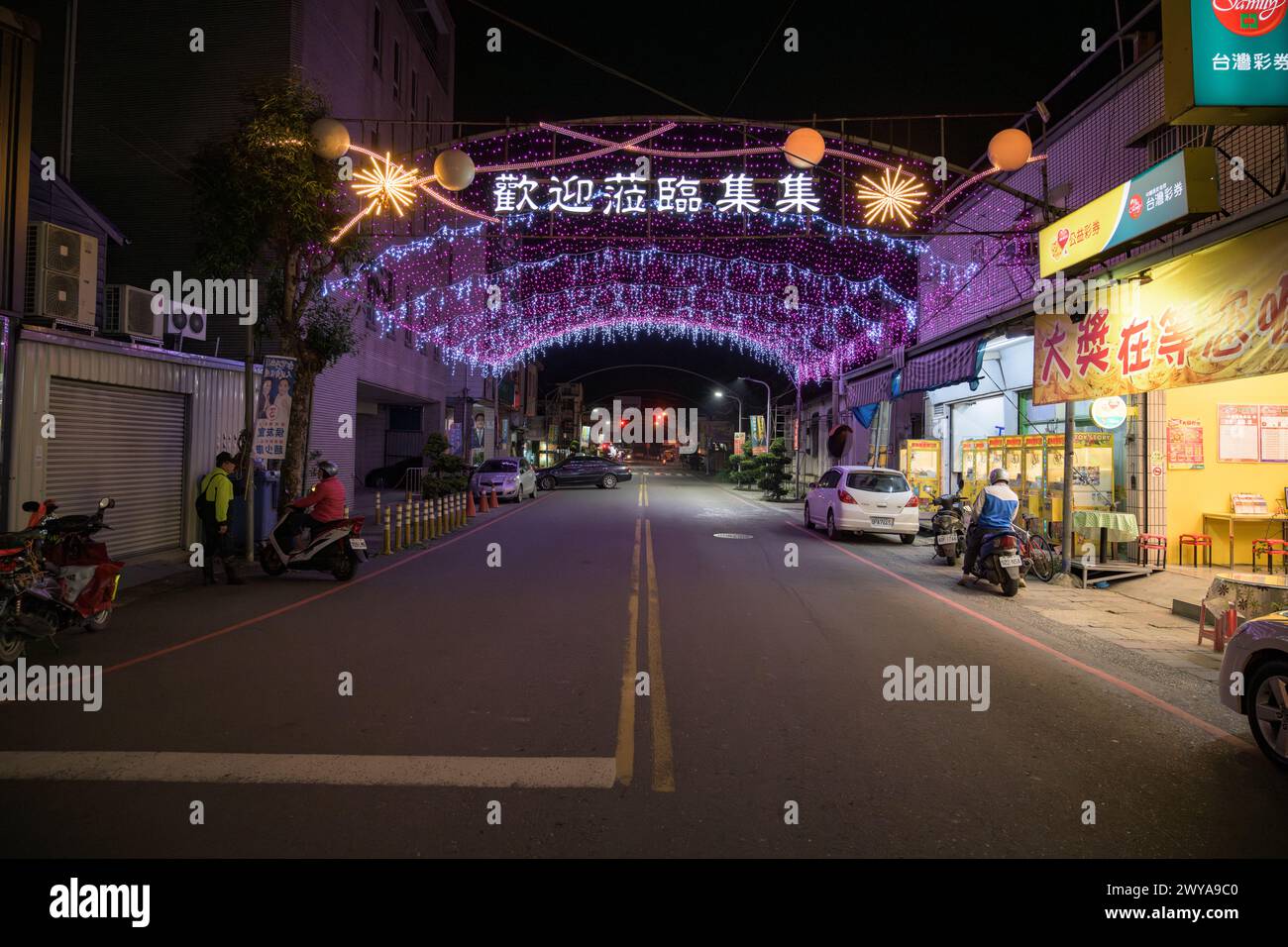 Una strada notturna vuota adornata da un baldacchino di scintillanti luci viola che creano un'atmosfera festosa e vivace Foto Stock