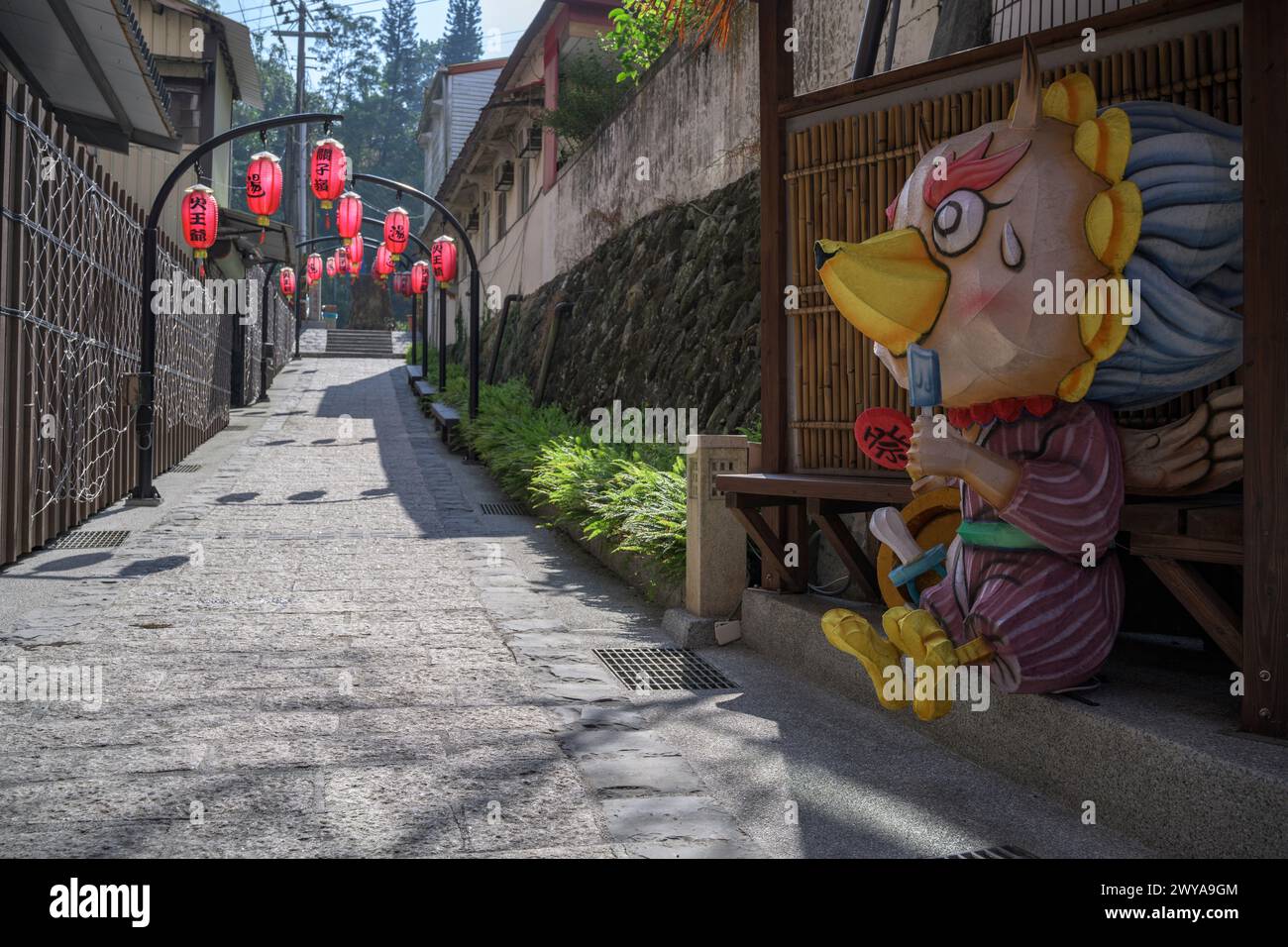Un tranquillo vicolo nelle sorgenti termali di Guanziling adornato da lanterne rosse e una figura di carta Foto Stock