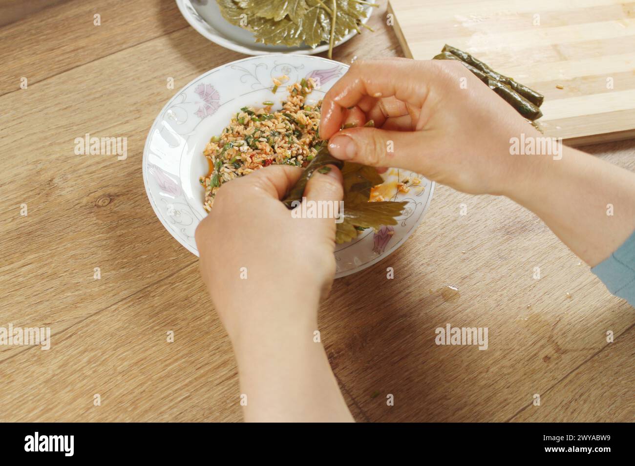 Mani di donna che preparano l'involucro ripieno di riso. Cucina greca o turca preparazione Yaprak Sarma o Dolma. Cibo tradizionale dell'egeo in Turchia. Foto Stock