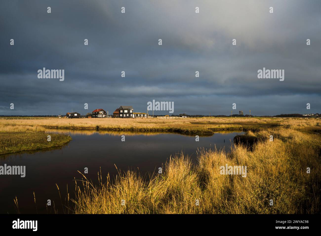 La luce del sole mattutina illumina le vecchie capanne dei pescatori al porto di Walberswick. Foto Stock