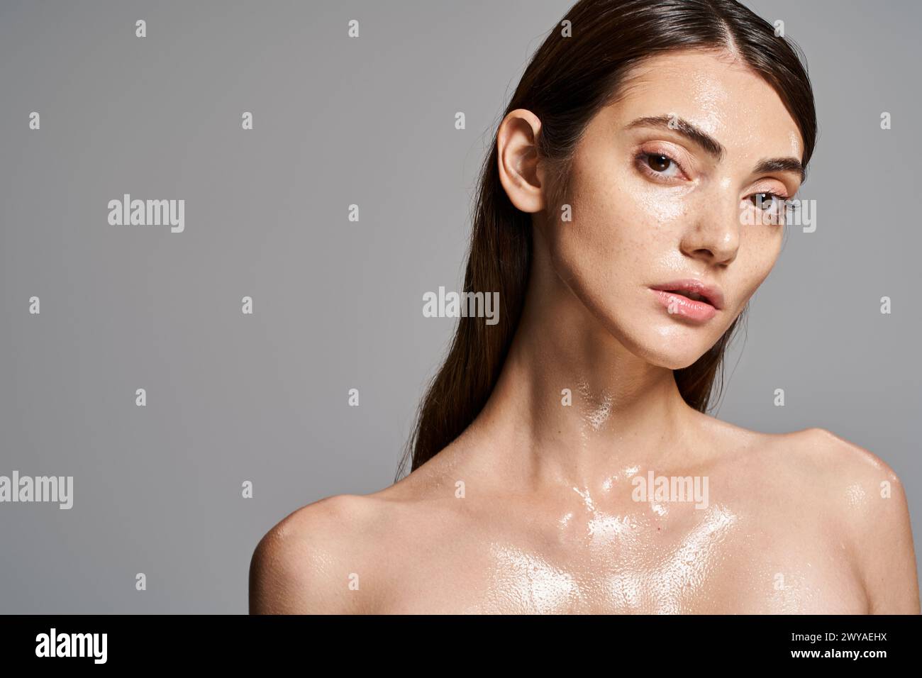 Una giovane donna caucasica con i capelli bruna e la pelle pulita ricoperta di goccioline d'acqua, creando un effetto ipnotizzante e rinfrescante. Foto Stock