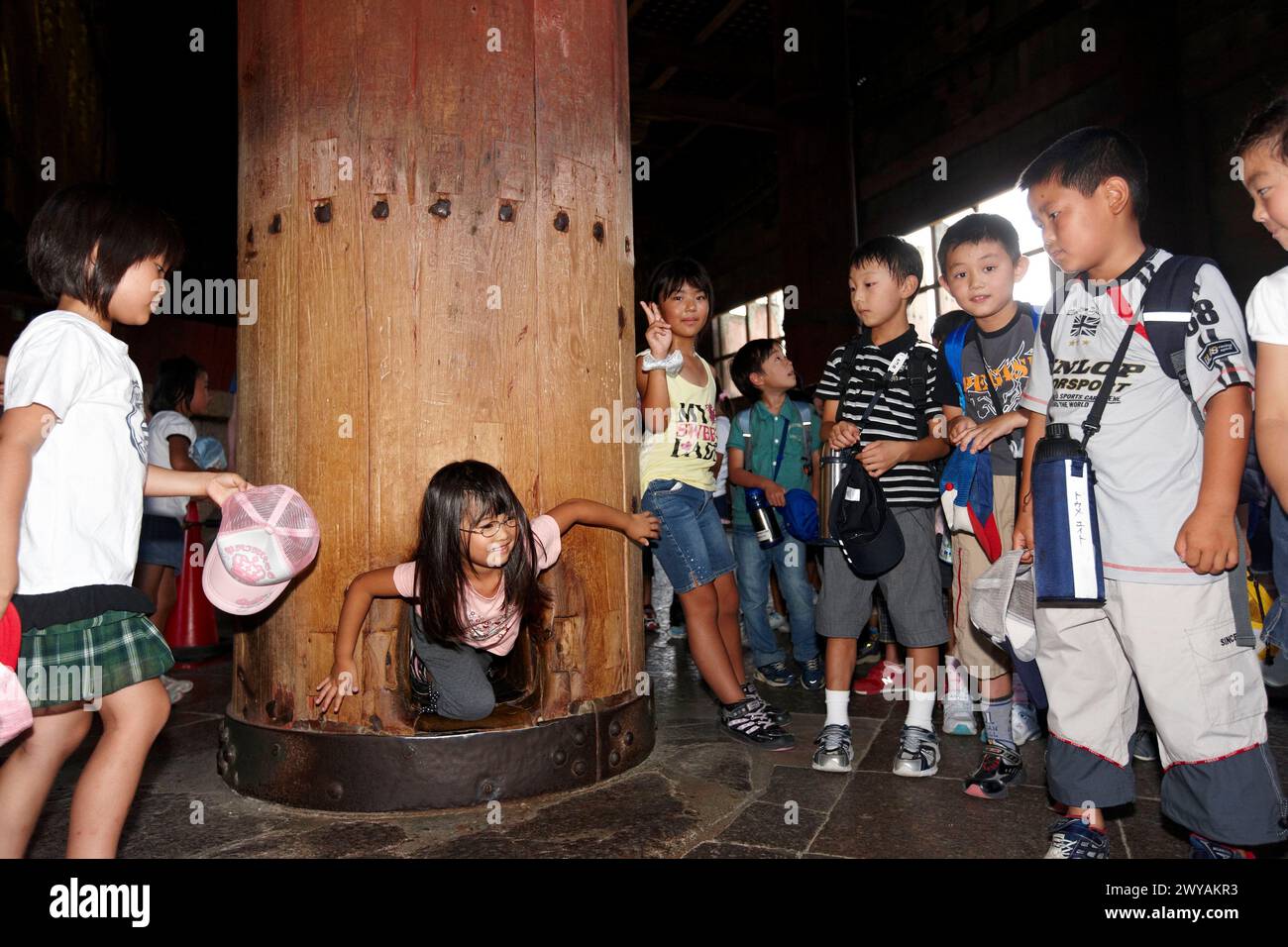 Bambino gattona anche se il foro nella colonna di legno per raggiungere il nirvana, il Grande Buddha, Tempio di Todai-ji di Nara, Giappone. Foto Stock