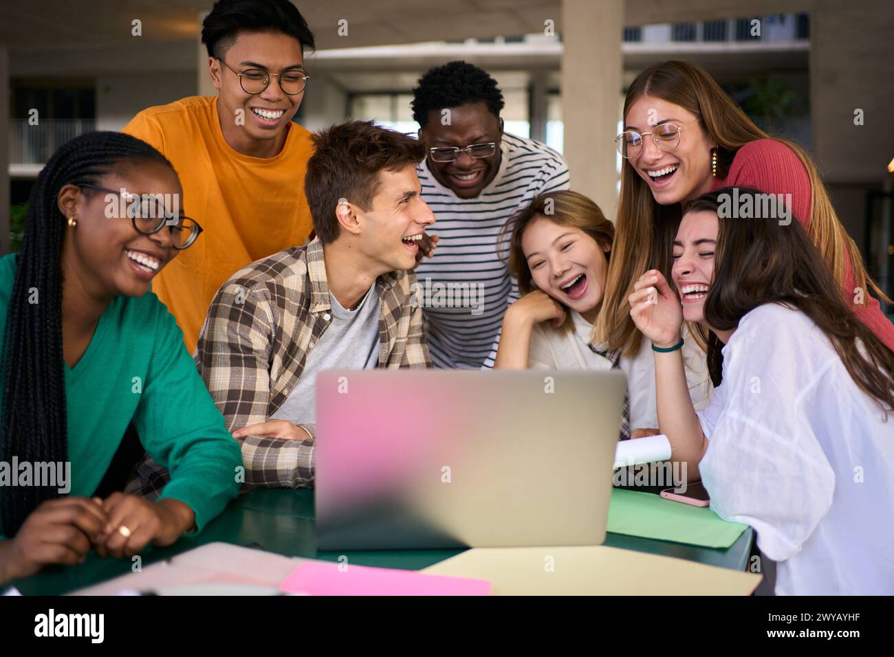 Gruppo di giovani studenti e persone che ridono usando un computer portatile nella caffetteria del campus universitario Foto Stock