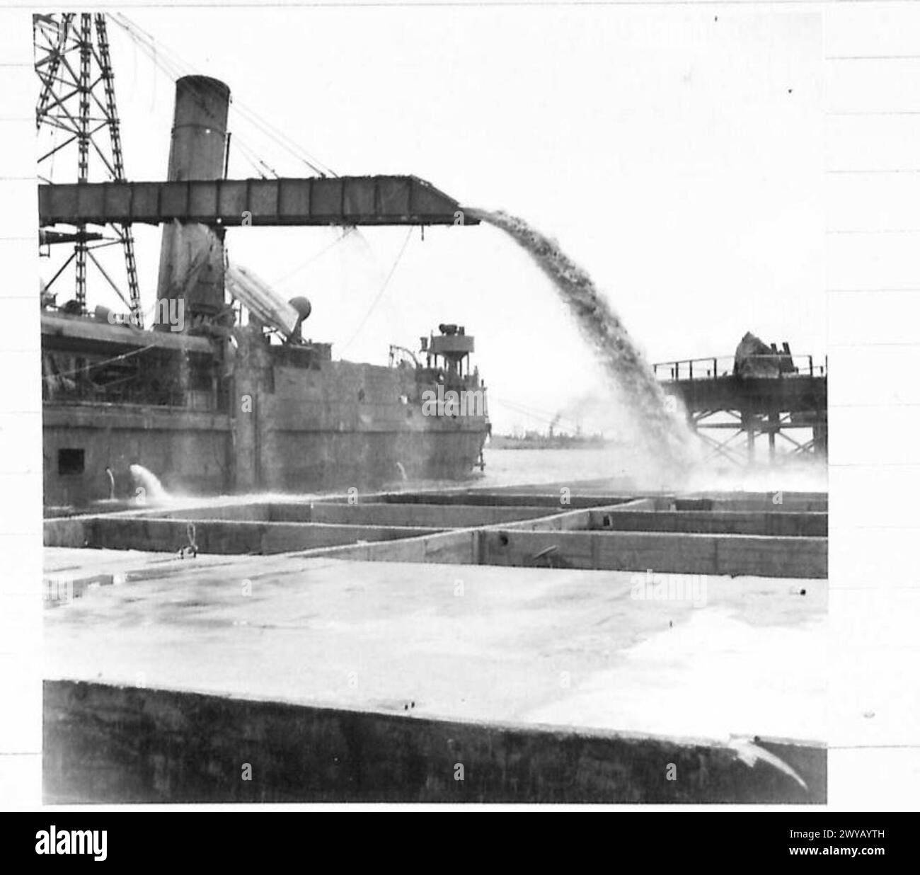 Una draga sta pompando sabbia in unità frantumatrici in calcestruzzo in una porta prefabbricata. L'operazione è documentata dall'esercito britannico del 21st Army Group durante le attività di costruzione in tempo di guerra. Foto Stock Una draga sta pompando sabbia in unità frantumatrici in calcestruzzo in una porta prefabbricata. L'operazione è documentata dall'esercito britannico del 21st Army Group durante le attività di costruzione in tempo di guerra. Foto Stock