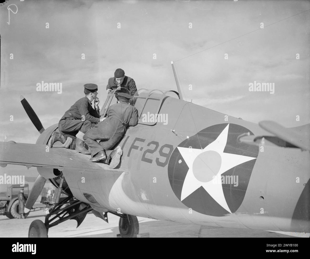 GLI AVIATORI DELLA MARINA DEGLI STATI UNITI ARRIVANO IN GRAN BRETAGNA. APRILE 1942, ROYAL NAVAL AIR STATION HATSTON. QUATTRO SQUADRONI DI AEREI DELLA US NAVY, COMPOSTI DA 9 BOMBARDIERI DOUGLAS TBD DEVASTATOR, 9 CACCIA GRUMMAN F4F WILDCAT E 29 BOMBARDIERI VOUGHT SB2U VINDICATOR SCOUT ARRIVARONO AD HATSTON PER COOPERARE CON IL BRACCIO AEREO DELLA FLOTTA. CON LORO CI SONO 65 PILOTI DELLA US NAVAL E 200 DISPARI RADIOMEN, CANNONI AEREI E RISERVE. - Un marinaio americano spiega il caccia Grumman ad un paio di marinai britannici. , Foto Stock