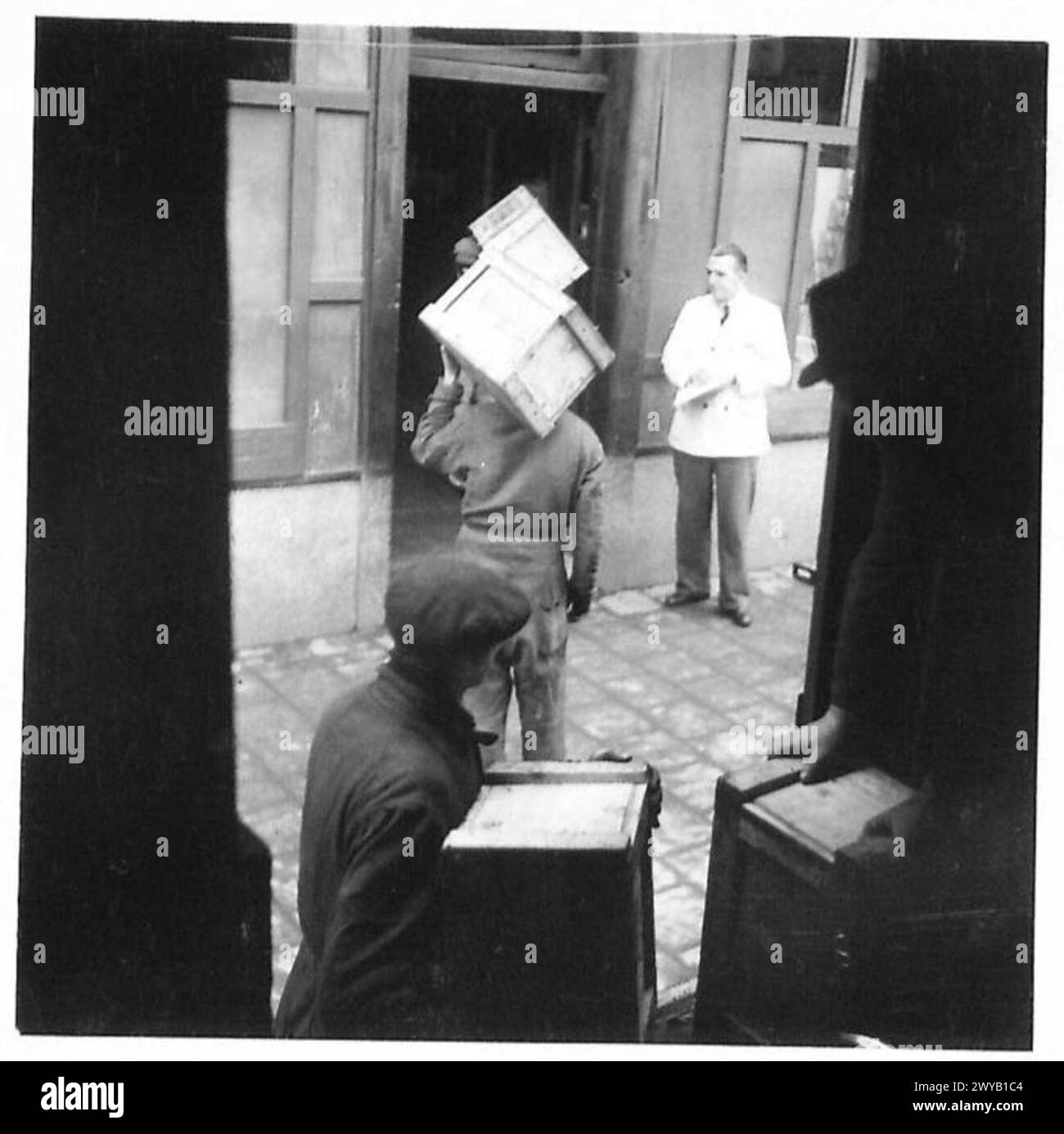 Un camion consegna le forniture al negozio di un rivenditore a Helmond, Olanda. Un rivenditore ispeziona i casi in arrivo mentre l'esercito britannico controlla la distribuzione nelle aree liberate. Foto Stock