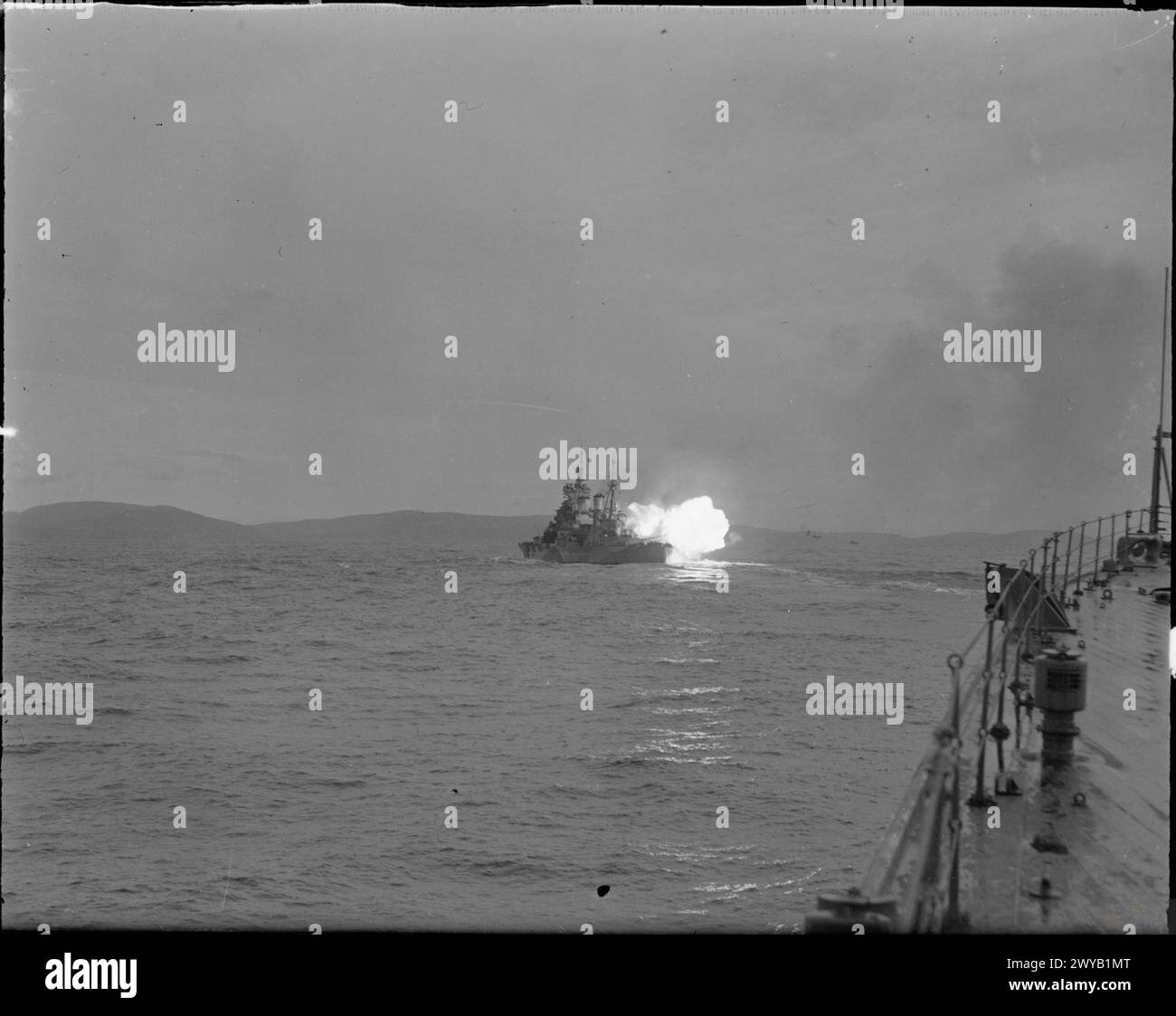 LA ROYAL NAVY DURANTE LA SECONDA GUERRA MONDIALE - Una vista della HMS HOWE sparò i suoi cannoni da 14 pollici vicino a Scapa Flow. Il brillante flash delle pistole che precede il fumo cordite dura solo per una frazione di secondo. , Royal Navy, HOWE (HMS) Foto Stock