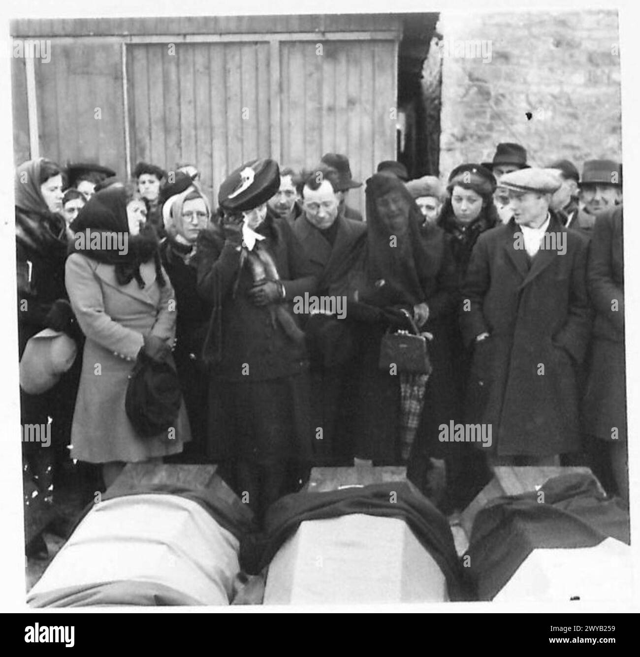 FUNERALE DELLE VITTIME della "BANDA" - didascalia originale in tempo di guerra: Le donne in lutto delle vittime, stanno pateticamente accanto alle bare dei loro cari. Negativo fotografico, British Army, 21st Army Group Foto Stock