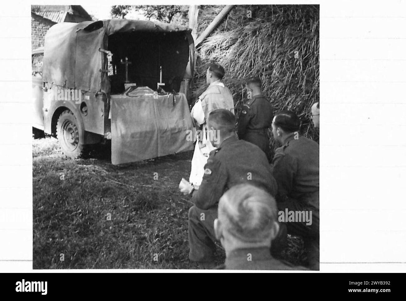 Padre C.V. Murphy celebra la messa sulla sponda del suo veicolo utilitario in un campo olandese vicino alla linea del fronte, con i soldati che partecipano alla congregazione e ricevono la Santa Comunione, l'esercito britannico, il 21st Army Group. Foto Stock