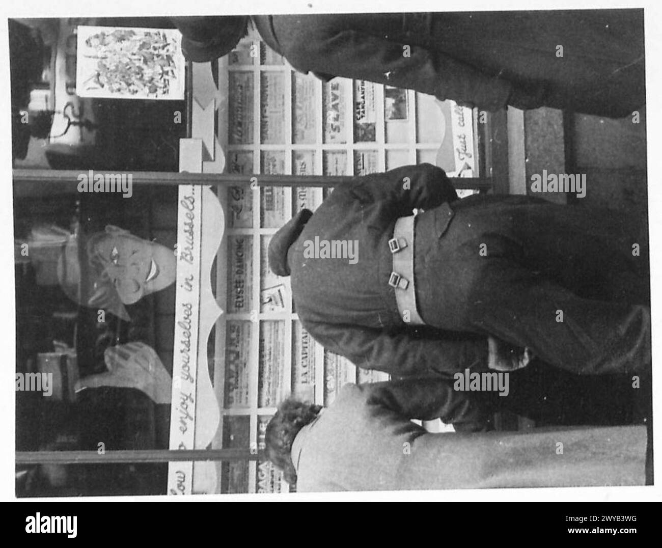 Un soldato in congedo a Bruxelles esamina una lista di intrattenimento in un negozio, British Army, 21st Army Group. Foto Stock