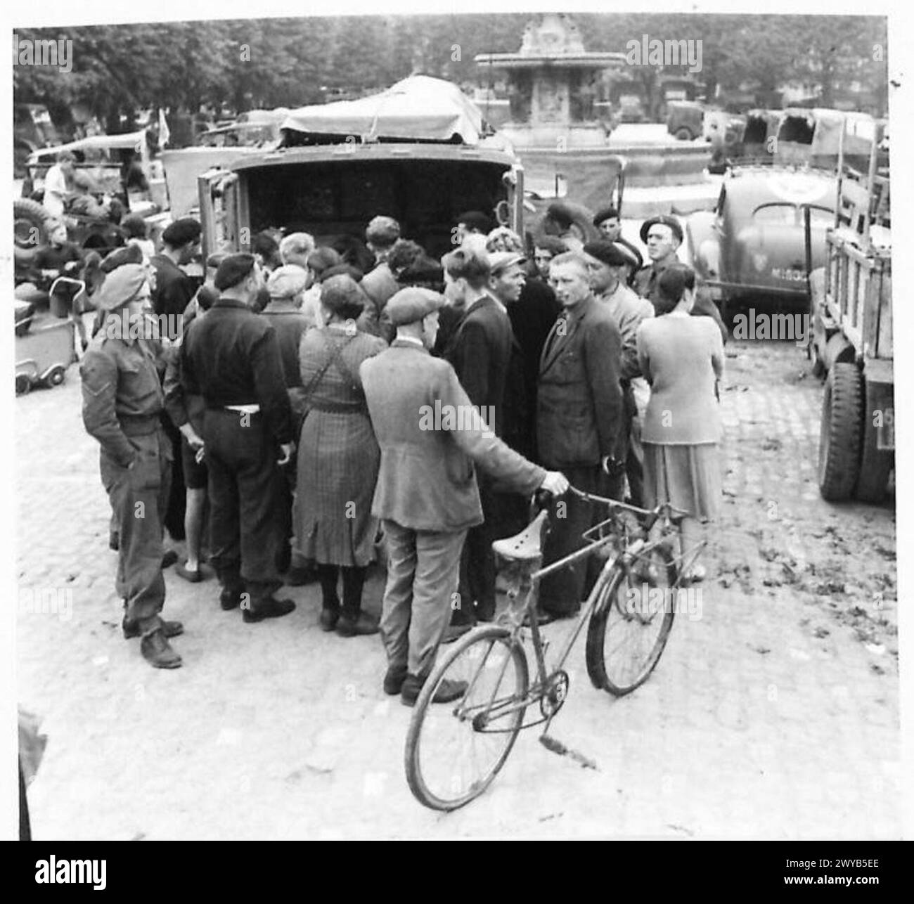 I cittadini francesi ascoltano una trasmissione nella piazza del mercato di Bayeux. Il British Army, 21st Army Group, documentò la scena durante la guerra. Foto Stock