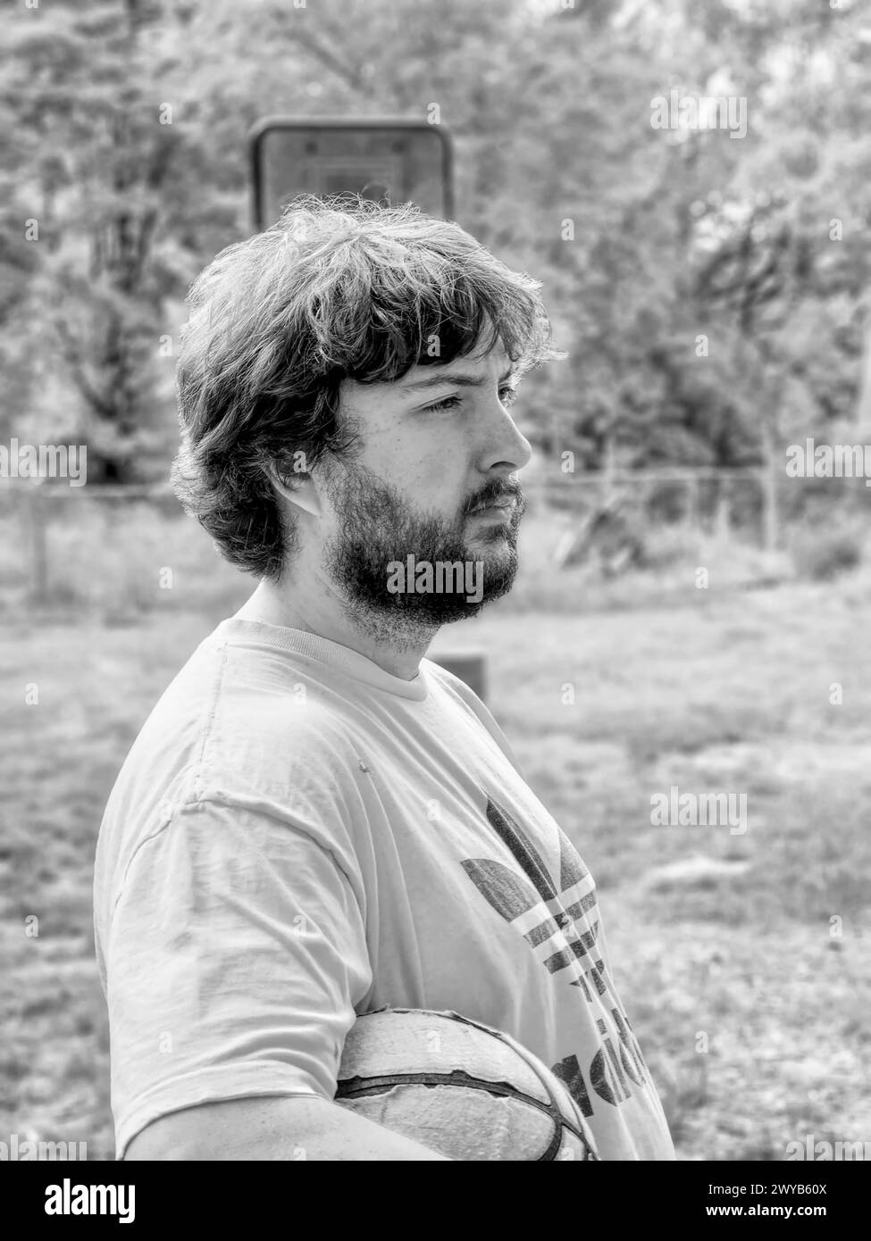 Un uomo fuori in un cortile, che tiene un pallacanestro Foto Stock