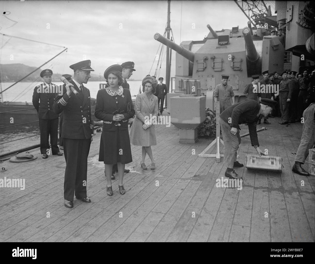 VISITA REALE ALLA HMS KING GEORGE V. 29 OTTOBRE 1944, GREENOCK. IL RE E LA REGINA ACCOMPAGNATI DALLA PRINCIPESSA ELISABETTA E DALLA PRINCIPESSA MARGHERITA FECERO UNA VISITA DI ADDIO ALLA CORAZZATA HMS KING GEORGE V PRIMA DI PARTIRE PER UNIRSI ALLA FLOTTA BRITANNICA DELLE INDIE ORIENTALI. - Comandante J G Long, RN, Comandante di RE GIORGIO V, che spiega la routine di munizioni alla Principessa Elizabeth. , Foto Stock