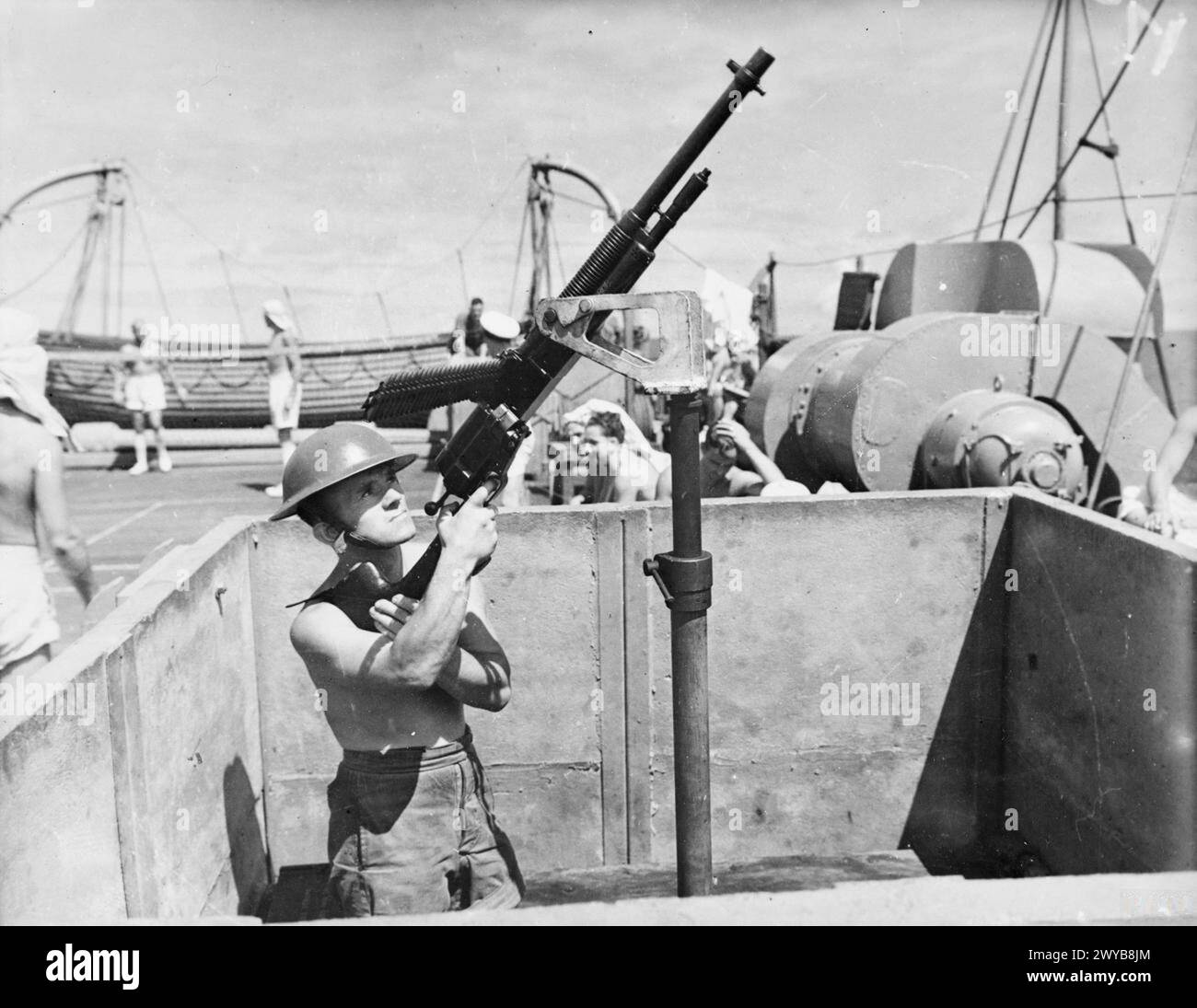 Un Gunner mans un Hotchkiss su trasporto truppe Empress of Australia mentre il deck tennis viene giocato durante un convoglio africano nell'agosto 1941. Foto Stock