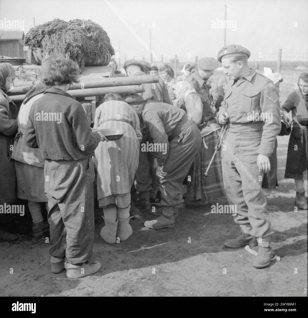 I detenuti del campo di concentramento di Bergen-Belsen si arrampicano per ottenere acqua potabile fresca durante la liberazione nell'aprile 1945. Foto Stock