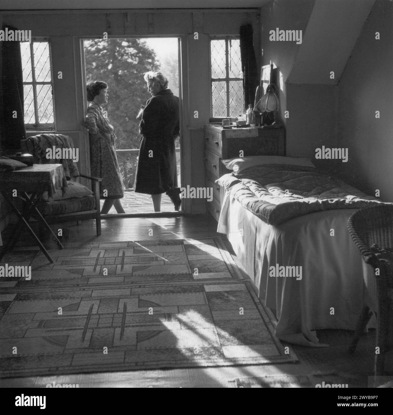 L'agente del welfare "Mrs R" del Consiglio del distretto rurale di High Wycombe visita un ostello locale evacuato nel 1944, parlando con il direttore in una camera da letto che si affaccia sul giardino. Foto Stock