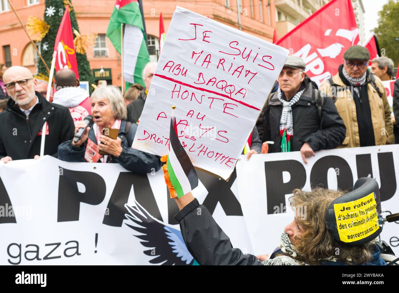 Una donna in poltrona con un cartello, io sono Mariam Abu Baqqa, vergogna sulla Terra dei diritti umani, davanti allo striscione, per la pace, ferma il massacro Foto Stock