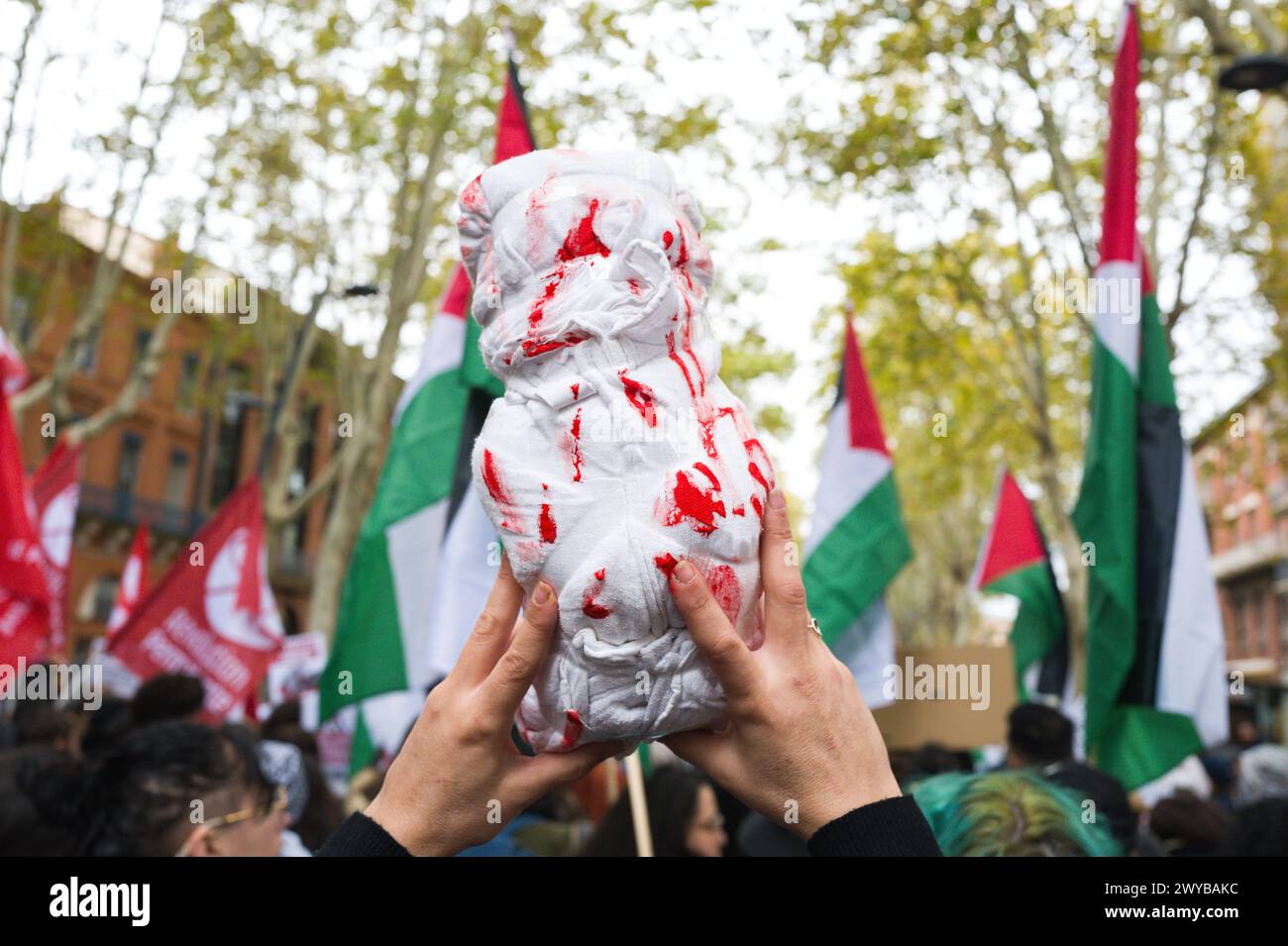 Una donna tiene a braccio una copertura colorata di rosso, che rappresenta un bambino morto, con bandiere palestinesi sullo sfondo.Patricia Huchot-Boissier Foto Stock