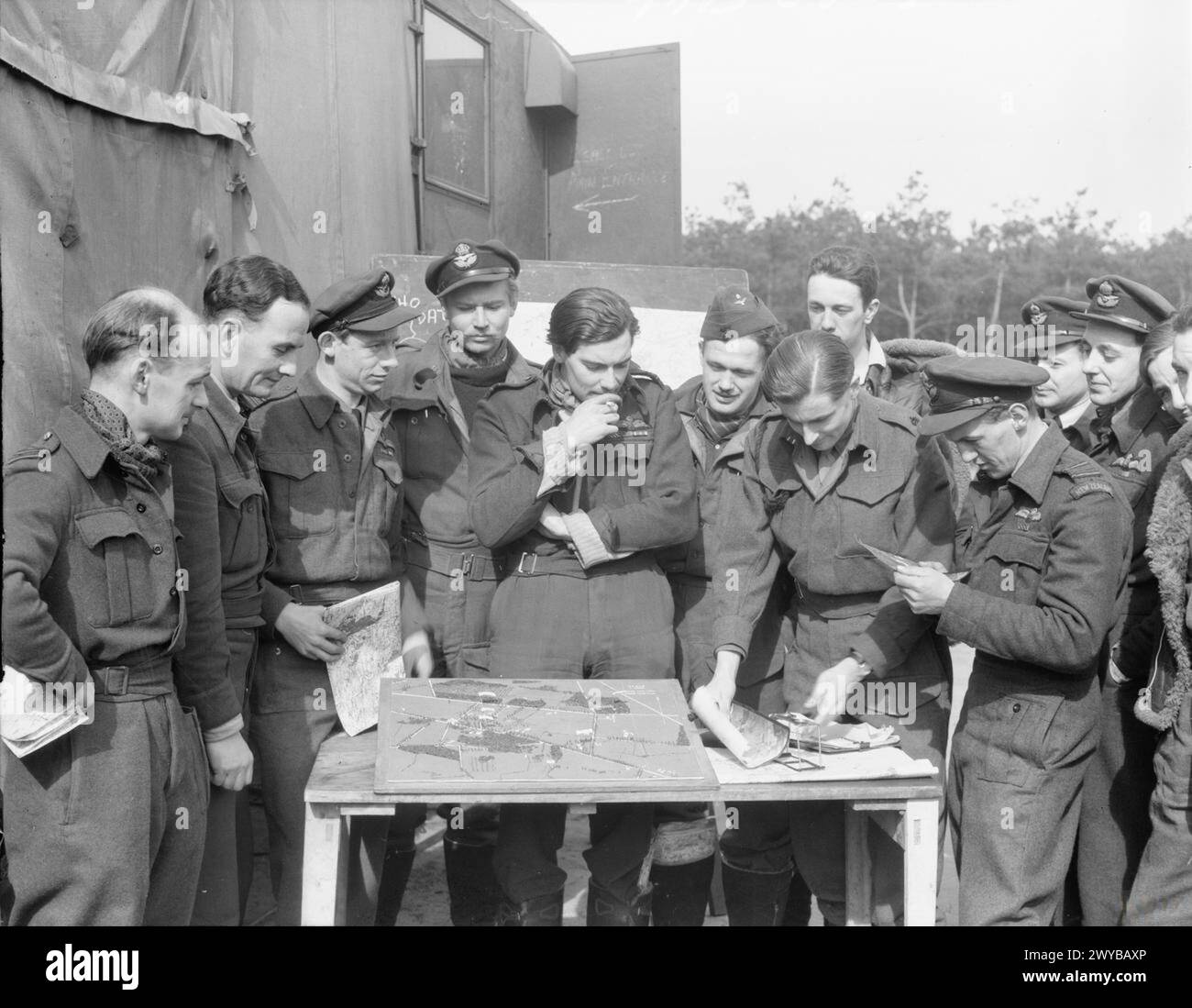 Un ufficiale di collegamento dell'esercito spiega ai piloti Hawker Typhoon del No. 123 Wing RAF a B77/Gilze-Rijen, Paesi Bassi, utilizzando fotografie e un modello in scala per un attacco al quartier generale del gruppo d'armate tedesco H, 1943-1945. Foto Stock