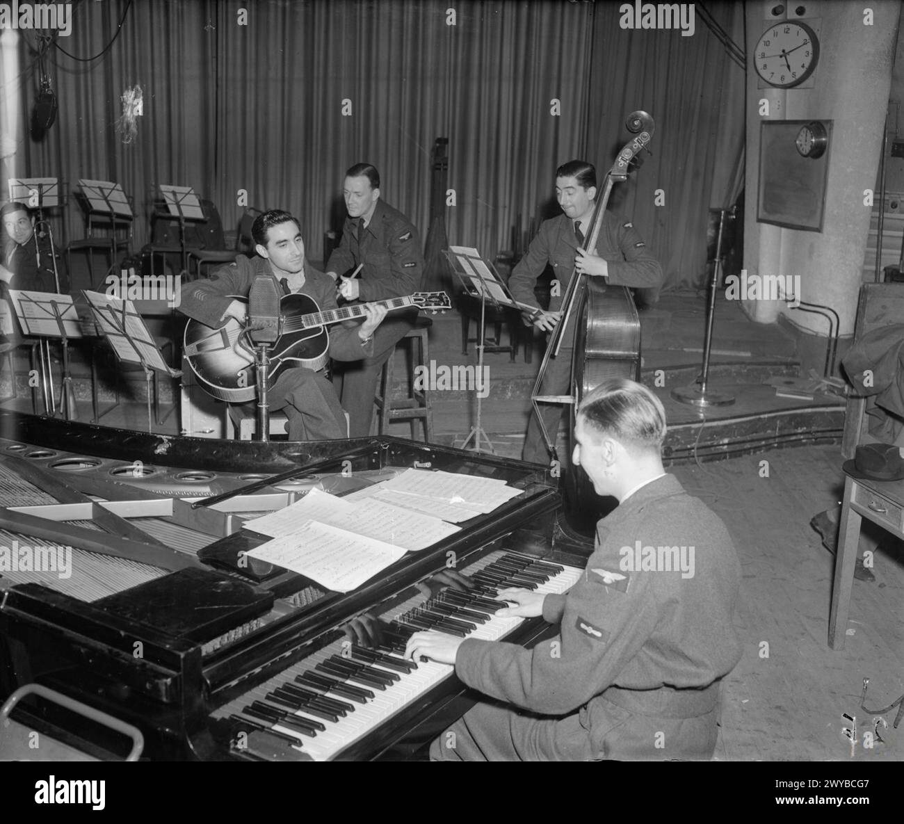 Quattro membri della RAF No. 1 Dance Orchestra, gli "Squadronaires", si esibiscono in una trasmissione dagli studi della BBC al Paris Cinema, Londra. Il pianista Ronny Aldrich suona in primo piano; vengono mostrati Sid Colin (chitarra), Jock Cummings (batteria) e Arthur Maden (contrabbasso, manager della band). Negativo fotografico, Royal Air Force, 1 Dance Orchestra. Foto Stock