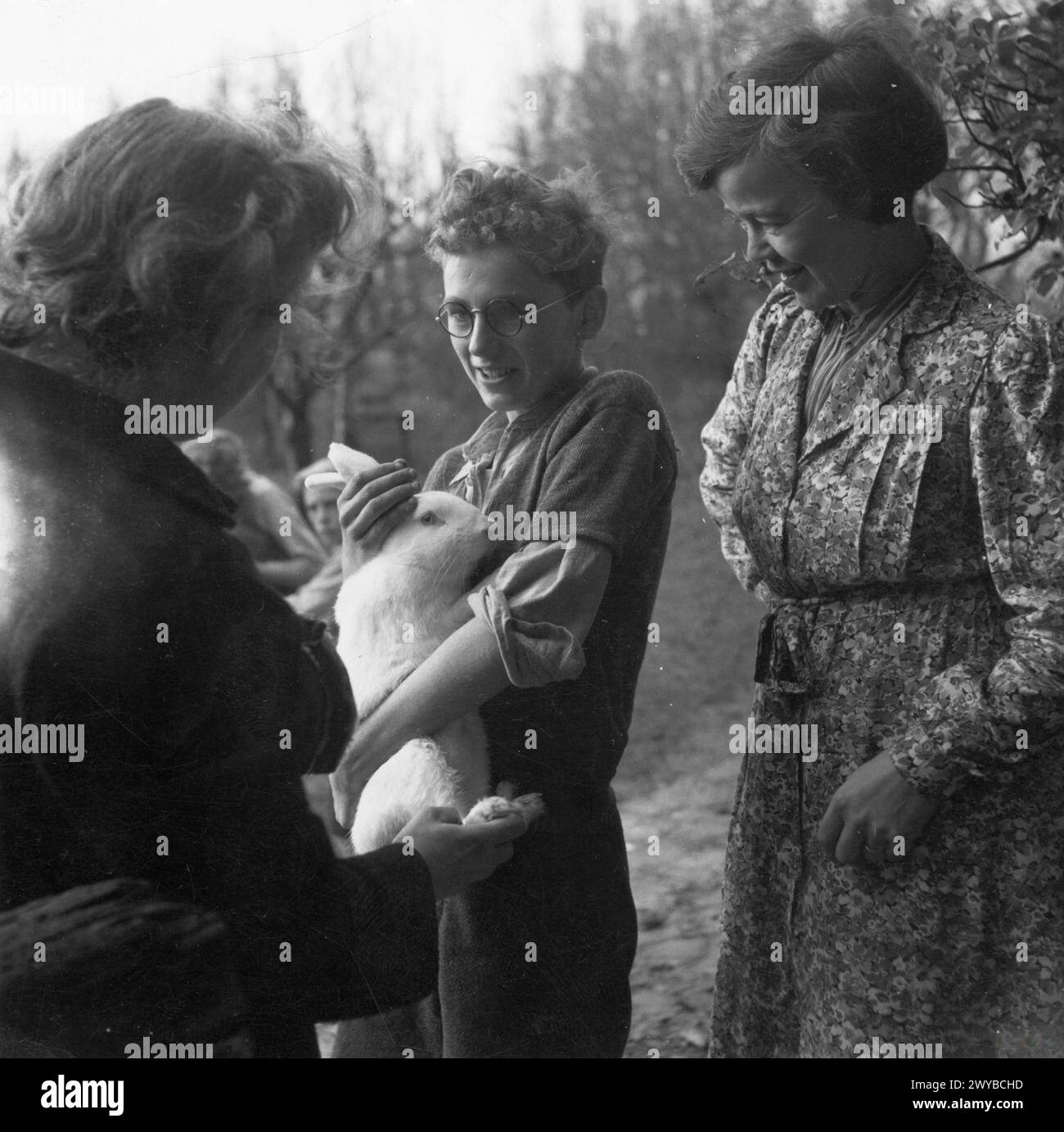 La signora R, agente del Welfare per il Consiglio del distretto rurale di High Wycombe, visita un ostello locale per gli sfollati a High Wycombe, Buckinghamshire, Inghilterra, 1944, parlando con il guardiano mentre un'evacuata mostra un coniglio nel giardino. Foto Stock
