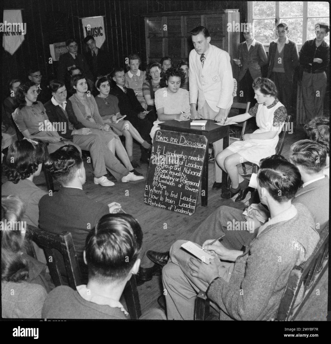 I membri di un gruppo di discussione sono impegnati in una sessione sulla leadership presso la Co-operative Youth Summer School, Windermere, Inghilterra, nel 1943. La lavagna mostra argomenti di discussione, tra cui la necessità di leadership, la formazione sulla leadership e la psicologia della leadership. Foto Stock