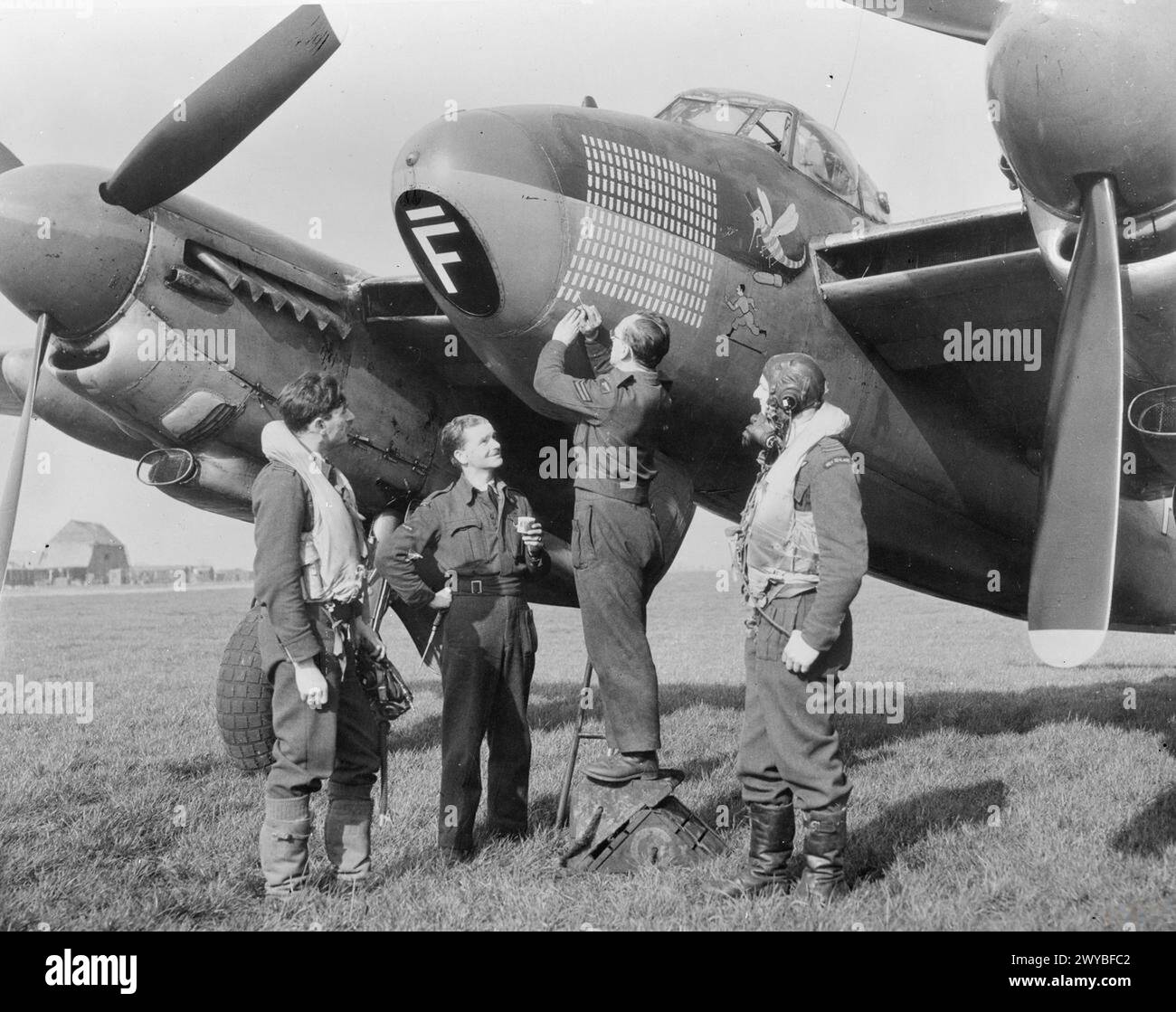Il caporale J Patterson registra la 203a sortita sulle operazioni di De Havilland Mosquito B Mark IX, LR503 "GB-F", del volo "C", No. 105 Squadron RAF a Bourn, Cambridgeshire, 1942-1945, osservata dai Luogotenenti di volo T P Lawrenson e D W Allen RNZAF. Foto Stock