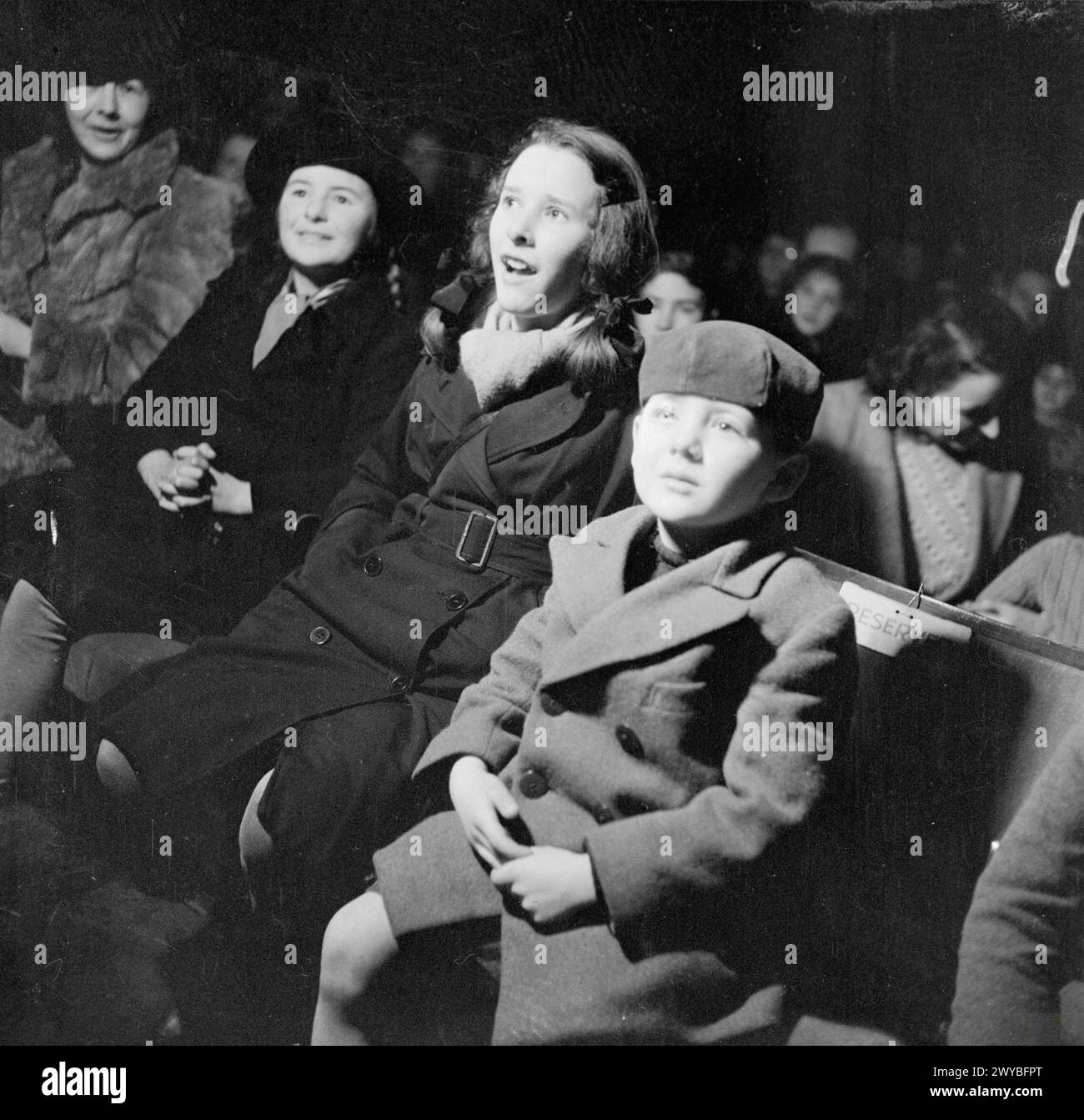 INTRATTENIMENTO IN TEMPO DI GUERRA, Regno Unito, 1942 - tre bambini siedono trasfissi mentre guardano una produzione di "Aladdin and His Magic Lamp" eseguita dalle WAAF in una base della Royal Air Force, da qualche parte in Gran Bretagna, forse RAF Bridgnorth. La fotografia mostra solo il pubblico: Nessuno degli artisti è visibile. , Royal Air Force, Women's Auxiliary Air Force Foto Stock