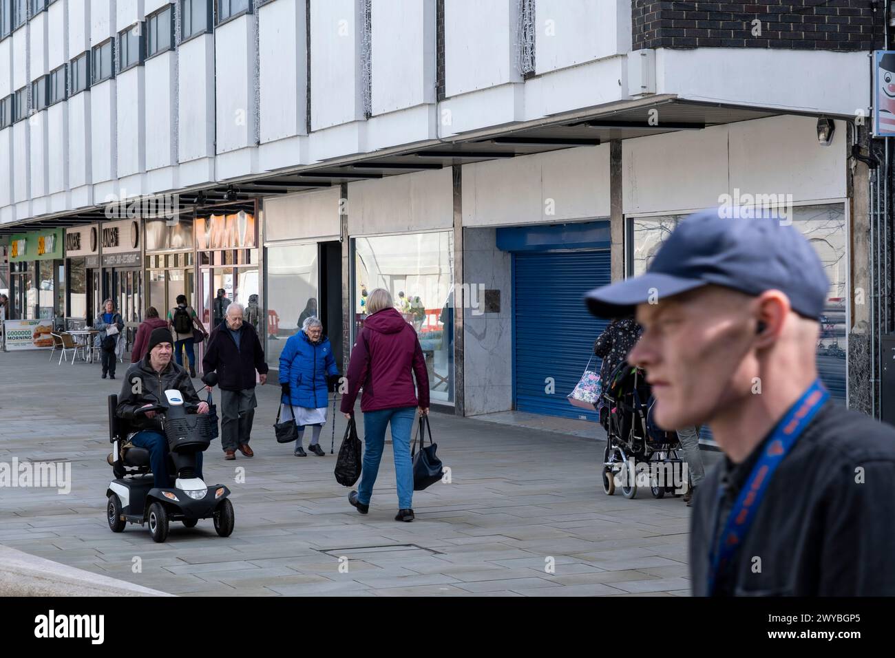 La gente passa davanti a spazi chiusi di vendita al dettaglio su Kings Square, un altro esempio del declino della strada principale del Regno Unito il 2 aprile 2024 a Gloucester, Regno Unito. Il centro di Gloucester è un esempio del declino della strada principale del Regno Unito e di quella che alcuni locali chiamano una “città morente” in quanto i grandi rivenditori si spostano e gli spazi al dettaglio chiudono, con ripercussioni sui posti di lavoro nella zona. Diversi fattori che contribuiscono si stanno allineando per portare al declino delle strade alte, tra cui la crisi del costo della vita, la stretta sui redditi delle famiglie dovuta all'inflazione e la caduta della sterlina post-Brexit, un cambiamento Foto Stock