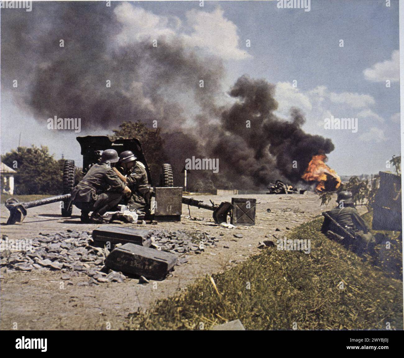 FOTOGRAFIE UFFICIALI A COLORI TEDESCHE DELLA SERIE 'DAS HEER Im GROSSDEUTSCHEN FREIHEITSKAMPF' [L'ESERCITO NELLA GRANDE LOTTA DELLA GERMANIA PER LA LIBERAZIONE], C 1941 - 1942 - Panzerjager truppe di un reggimento di granatieri uomo un cannone anticarro Pak 37mm durante un assalto lungo una strada sul fronte orientale. In lontananza, un veicolo brucia bruscamente. , Foto Stock