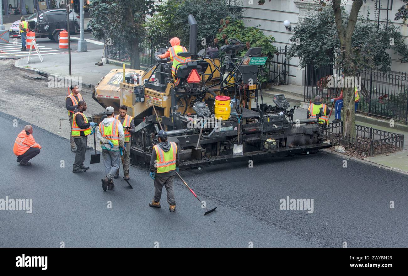 il lavoratore cittadino pavimenta la strada con un veicolo per pavimentazione (nuova installazione di asfalto su strade urbane) rullo vibrante tandem Foto Stock