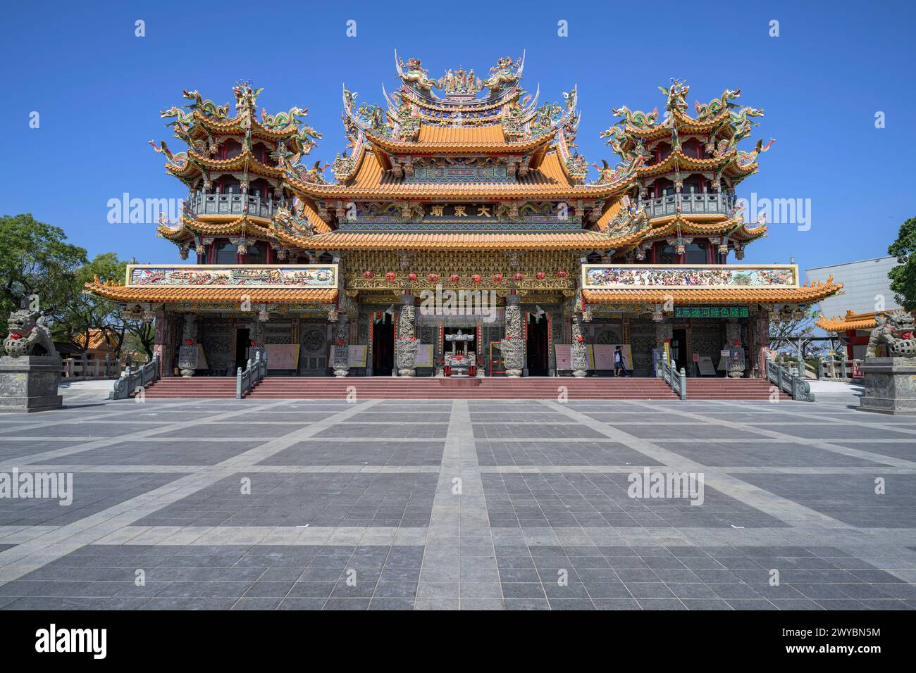 Maestoso tempio asiatico tradizionale che presenta un intricato design architettonico con elaborati tetti e una grande piazza aperta Foto Stock