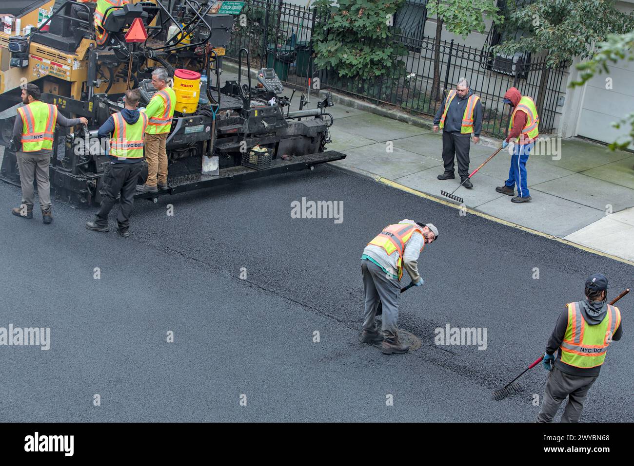 il lavoratore cittadino pavimenta la strada con un veicolo per pavimentazione (nuova installazione di asfalto su strade urbane) rullo vibrante tandem Foto Stock