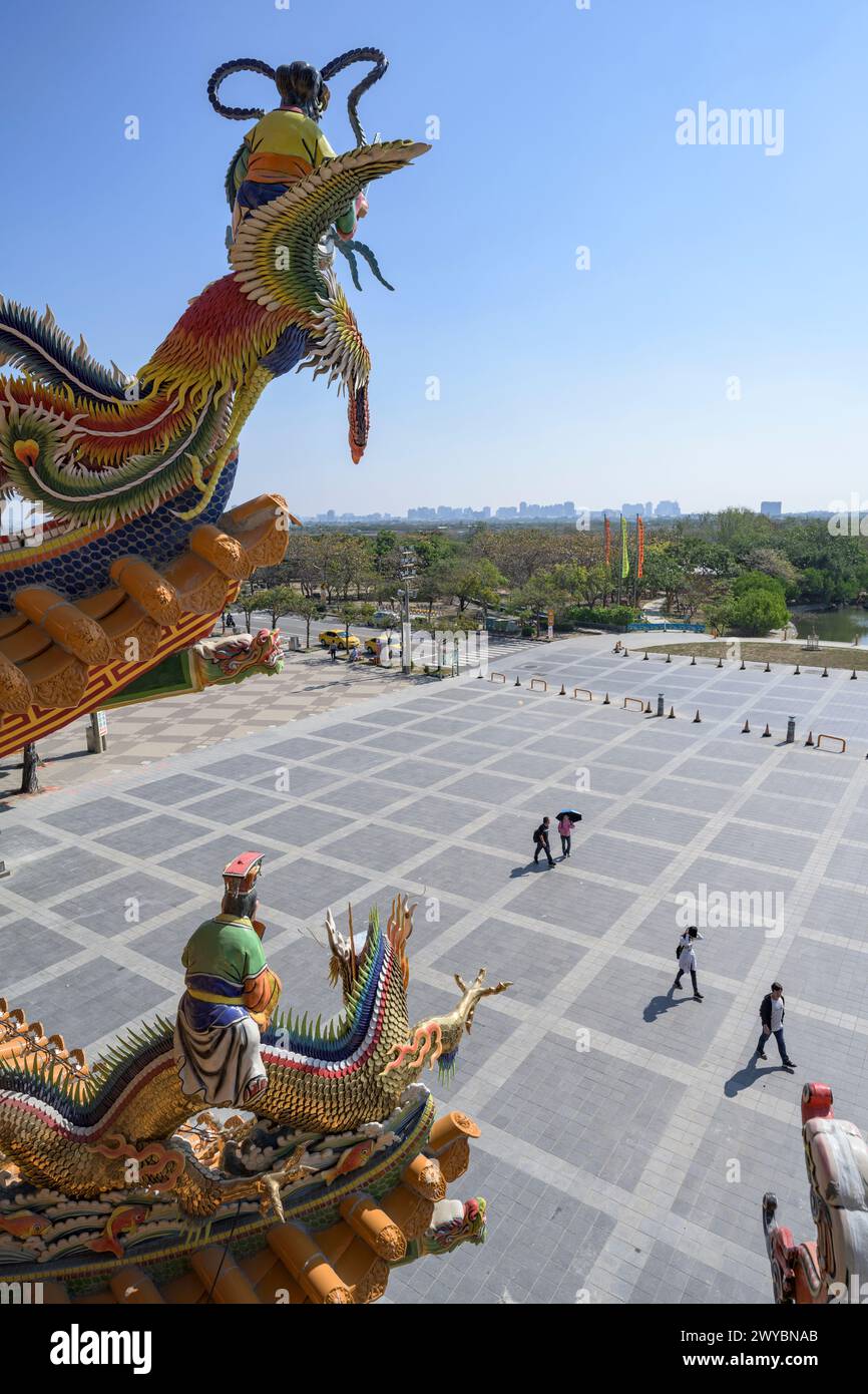 Maestosa statua del drago in cima a un tempio con una grandiosa vista del paesaggio urbano e delle persone che camminano sotto Foto Stock
