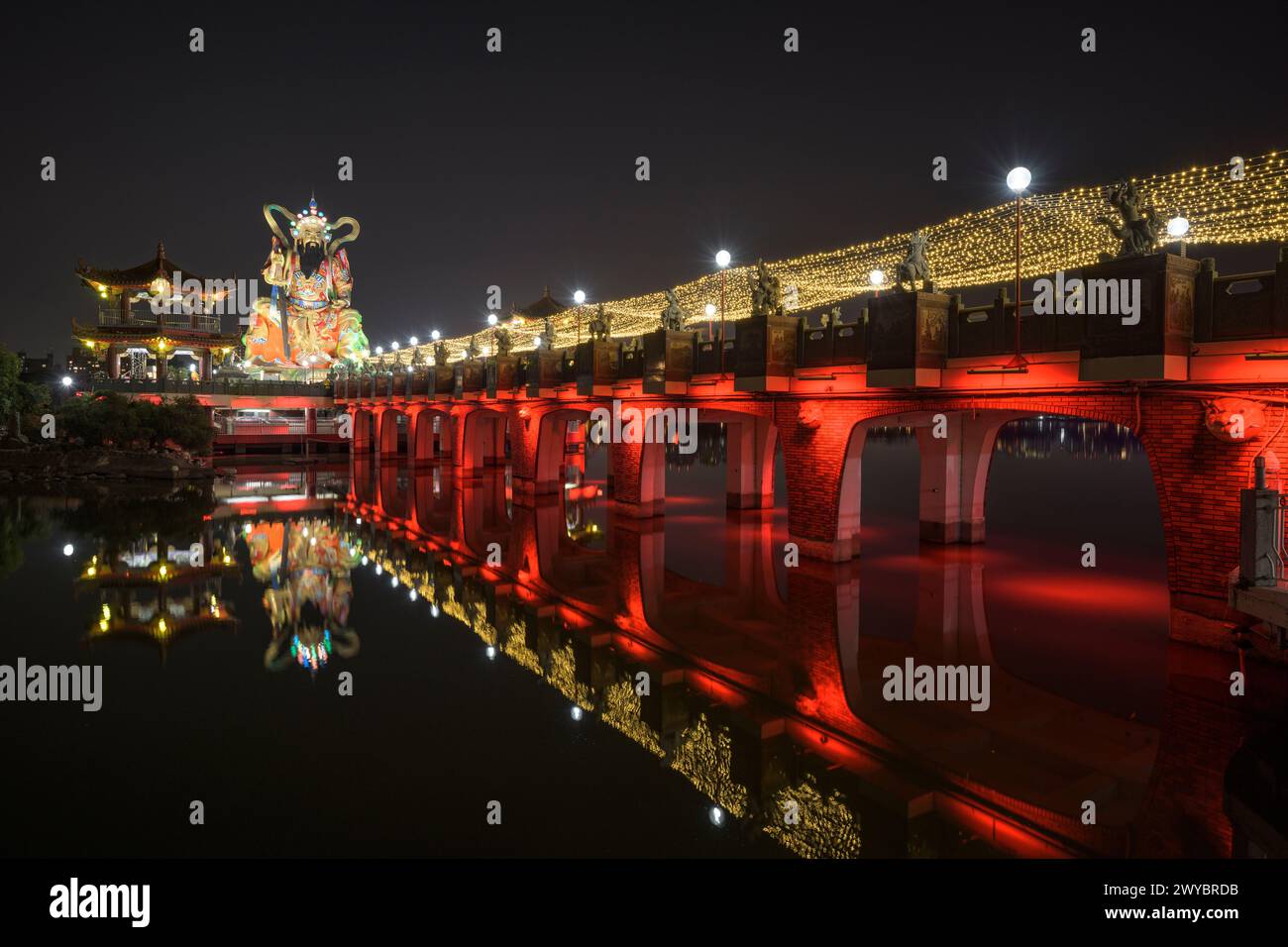 Una foto a lunga esposizione di un ponte del tempio Zuoying Yuandi decorato in modo luminoso e dei suoi riflessi sullo stagno del Loto Zuoying di notte Foto Stock