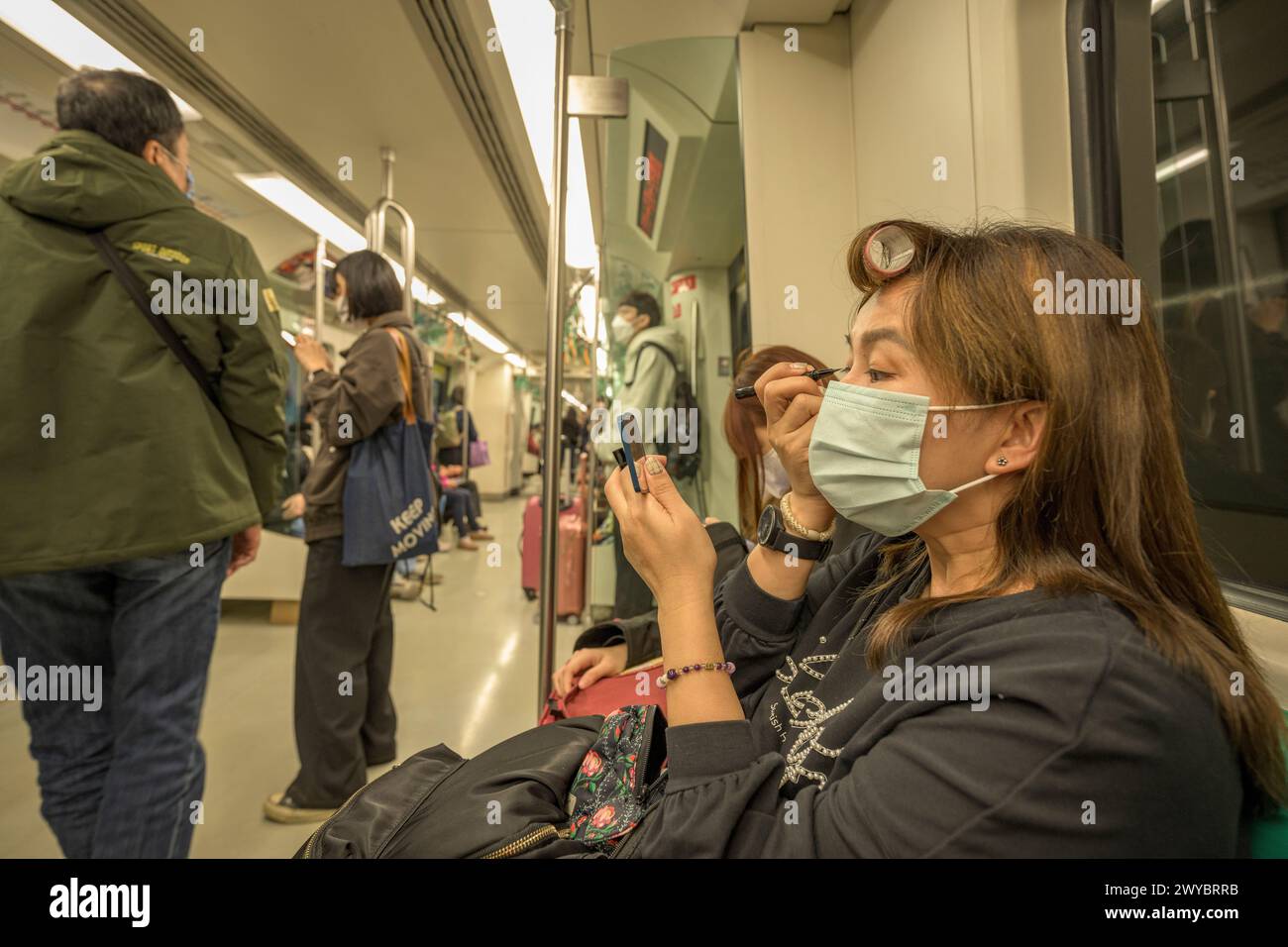Donna che si trucca gli occhi durante un lungo viaggio in metropolitana Foto Stock